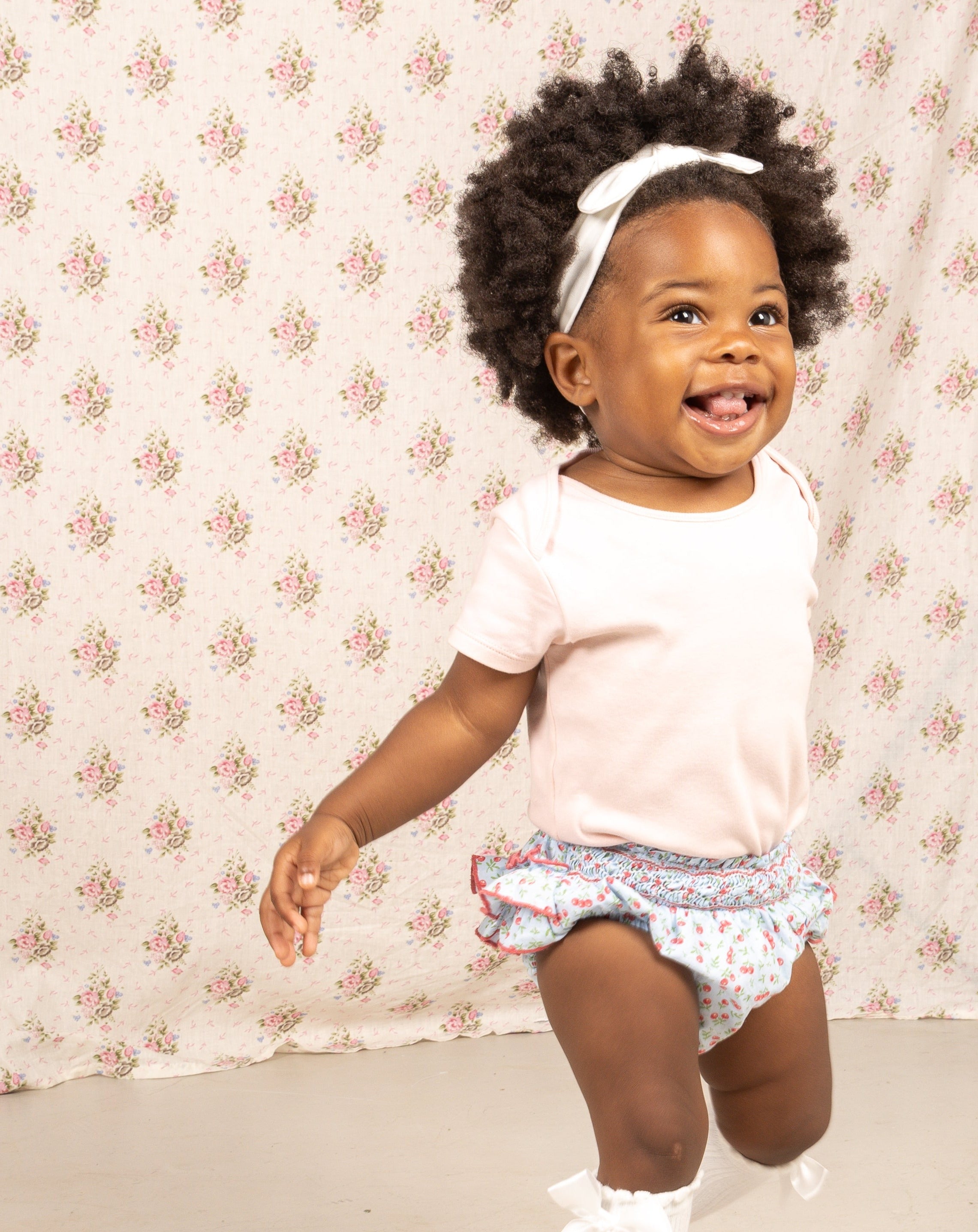 baby in cherry print shorts