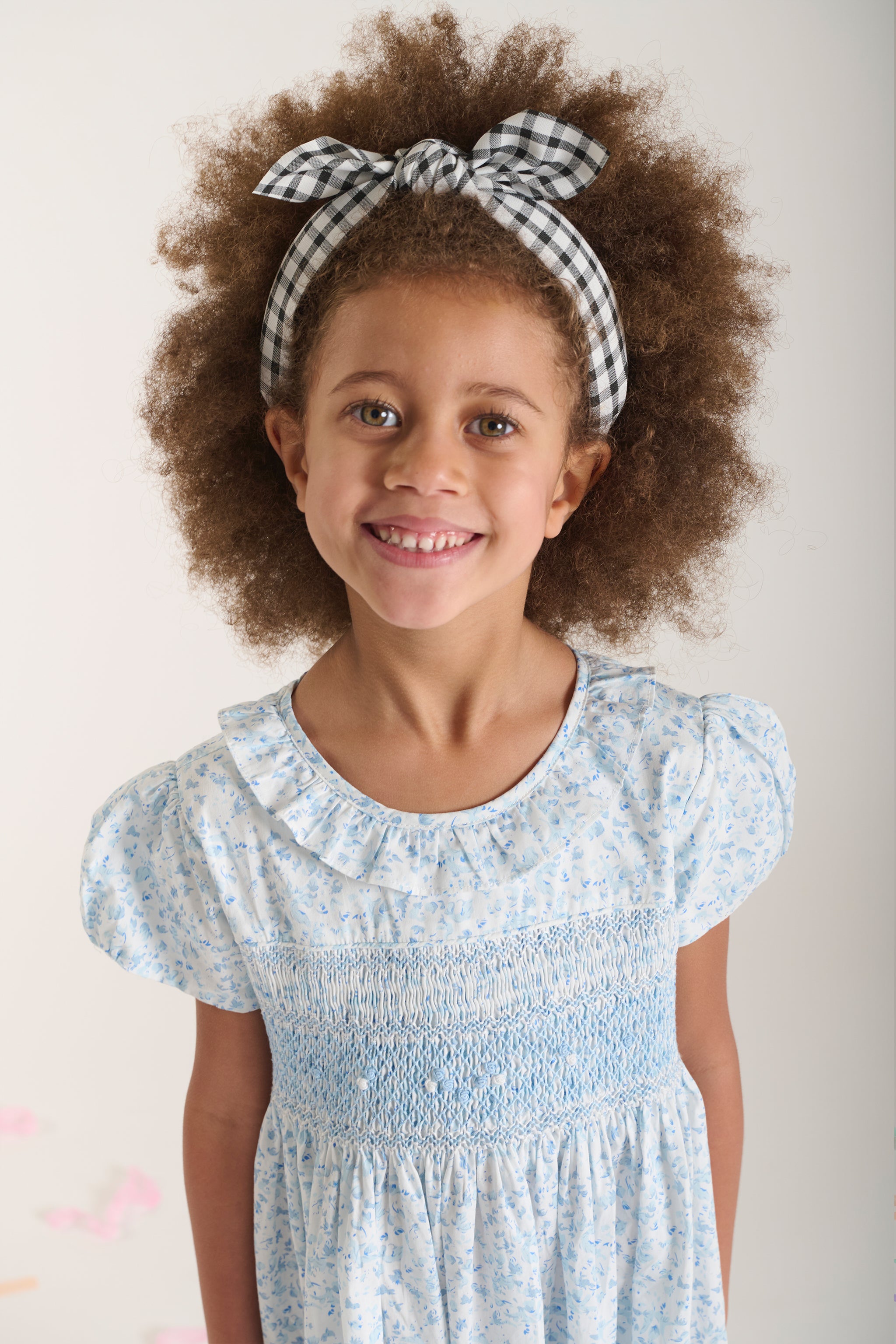 closeup of girl in hand-smocked white and blue floral dress