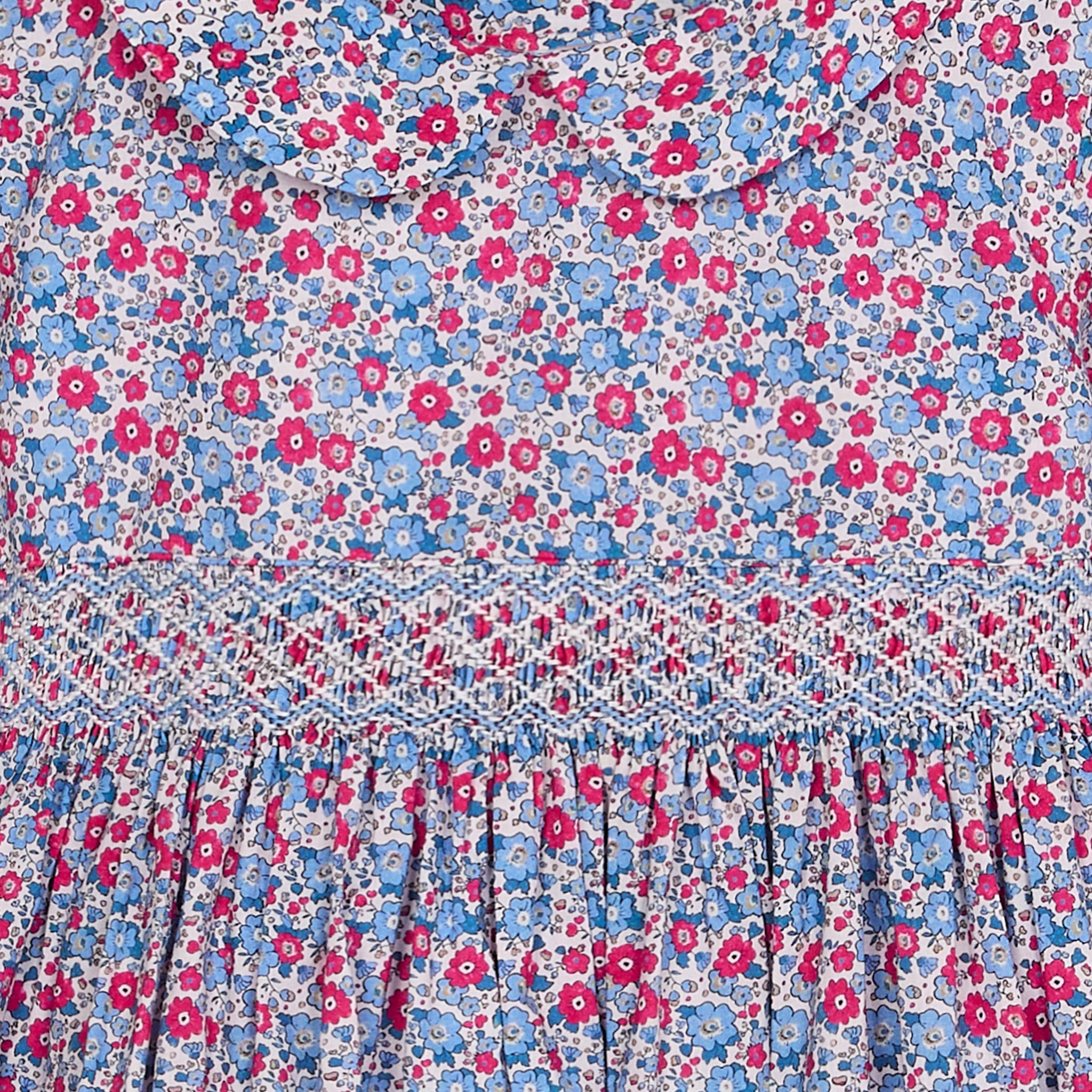 Floral patterned fabric with pink and blue flowers and hand smocking closeup