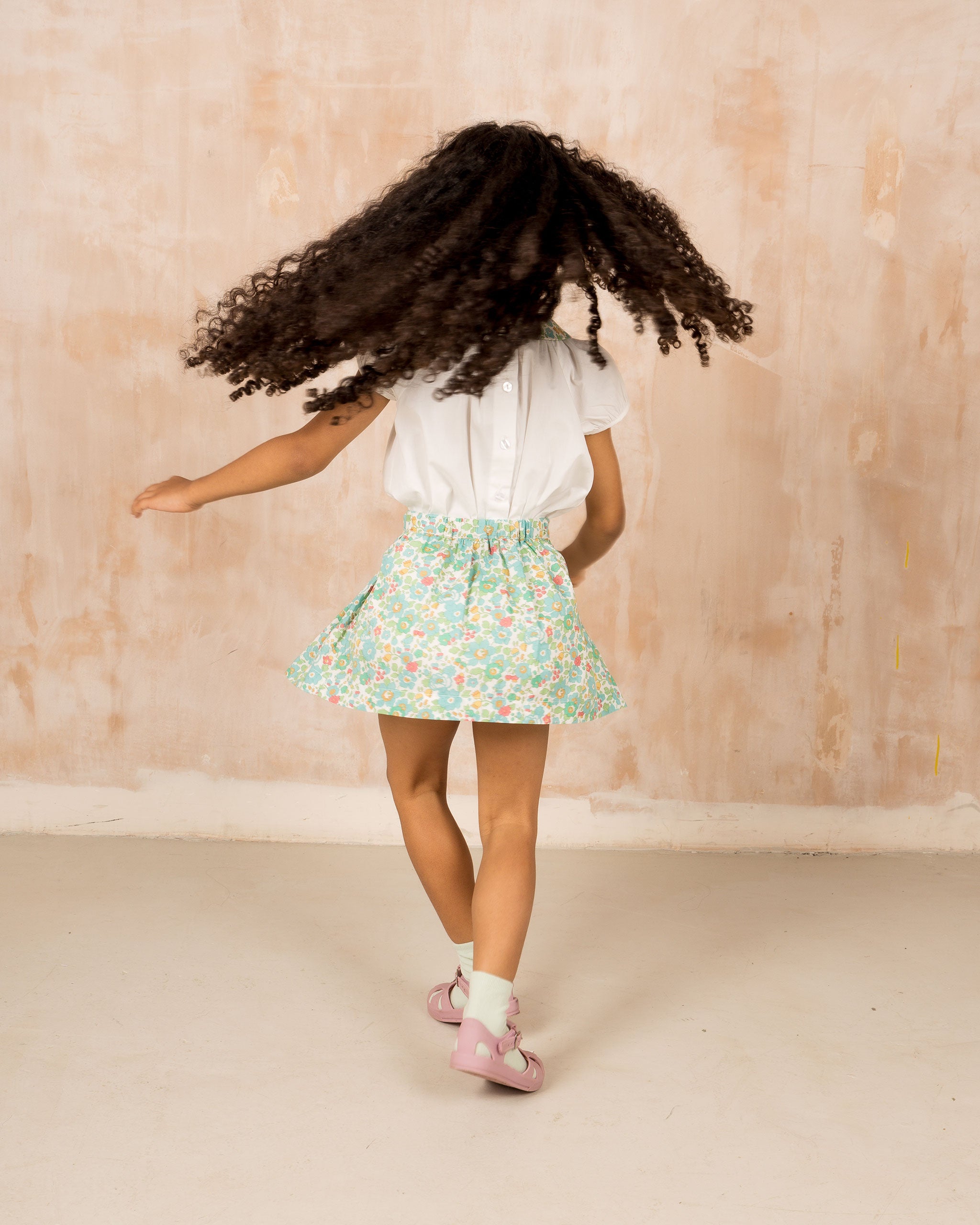 girl wearing smocked girls skirt, Liberty Betsy fabric, back view