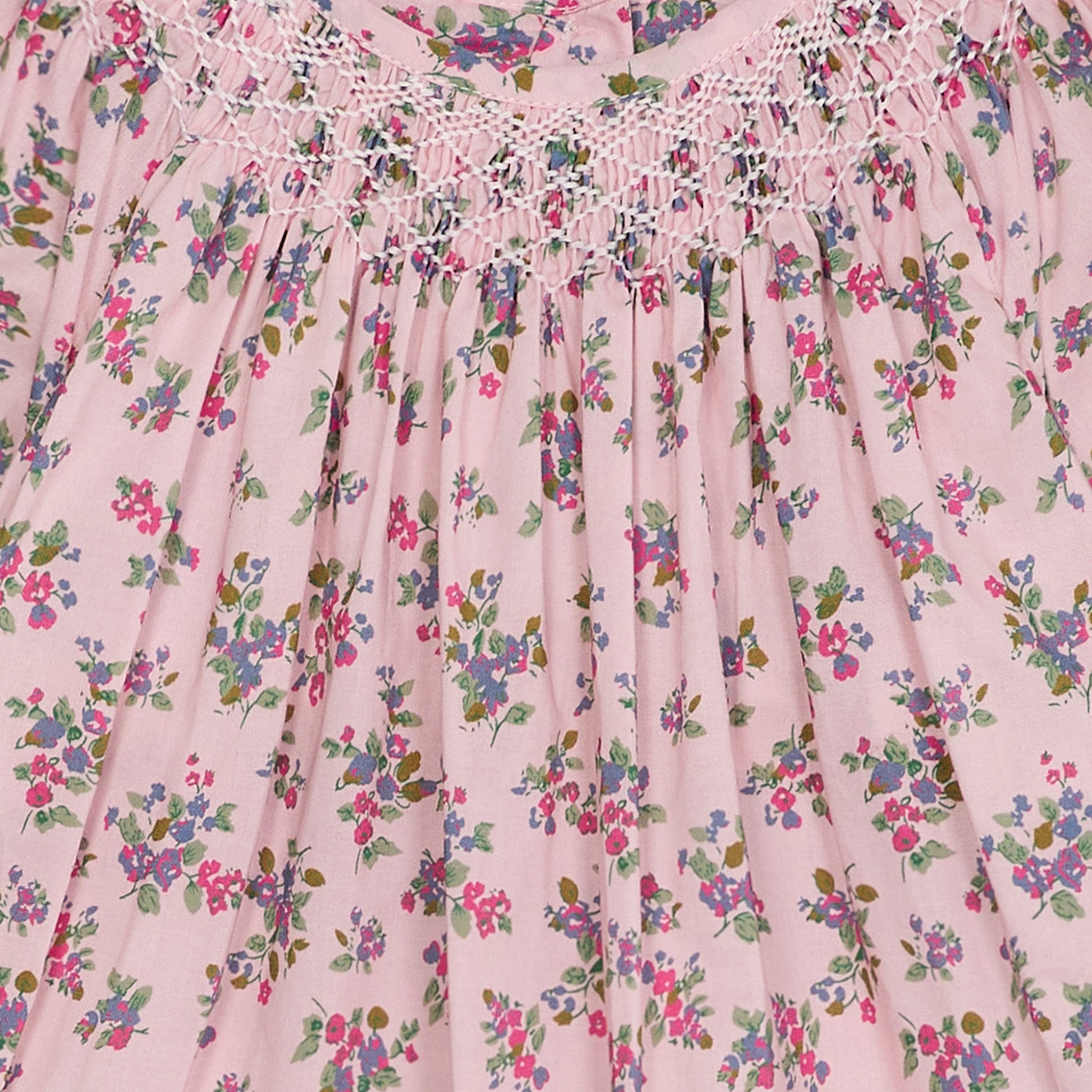 Close-up of a pink floral dress with intricate smocking details.