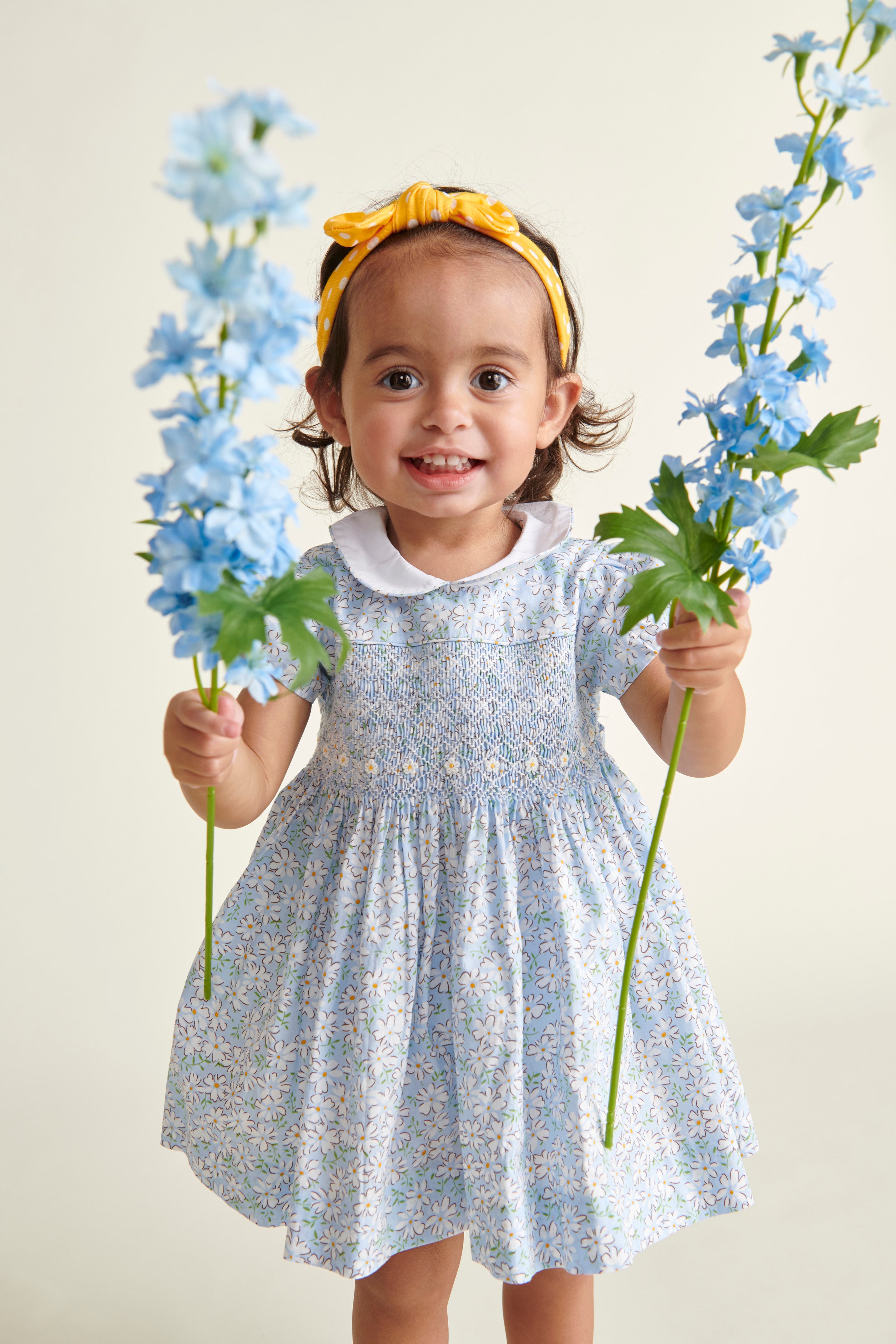toddler in blue hand-smocked dress holding flowers