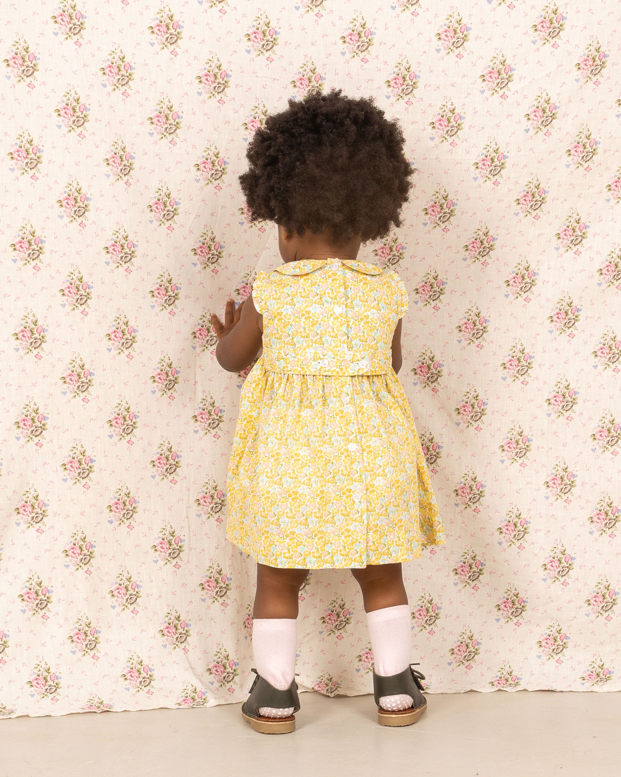 baby girl wearing smock dress, yellow, back view 
