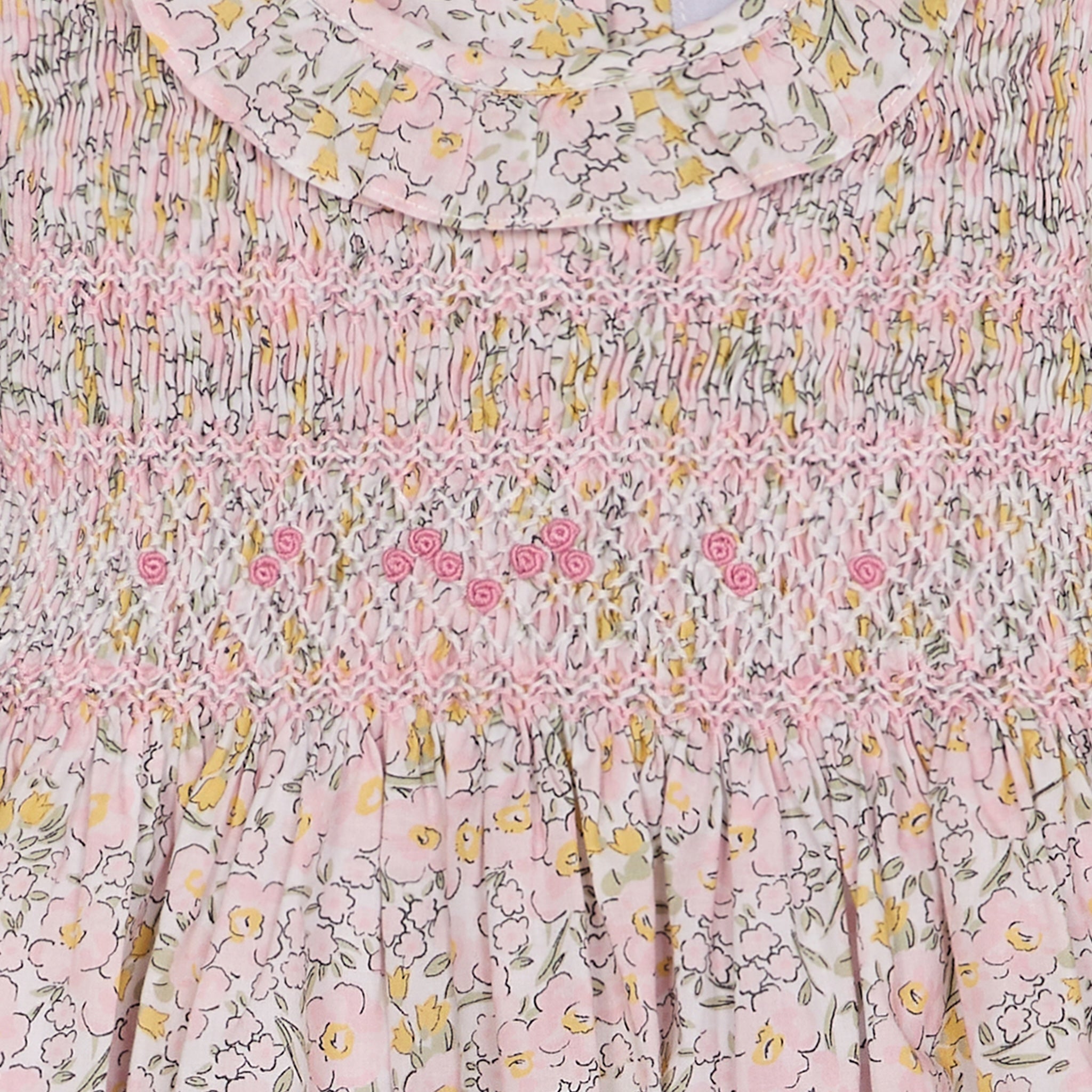 Floral patterned fabric with pink smocking closeup