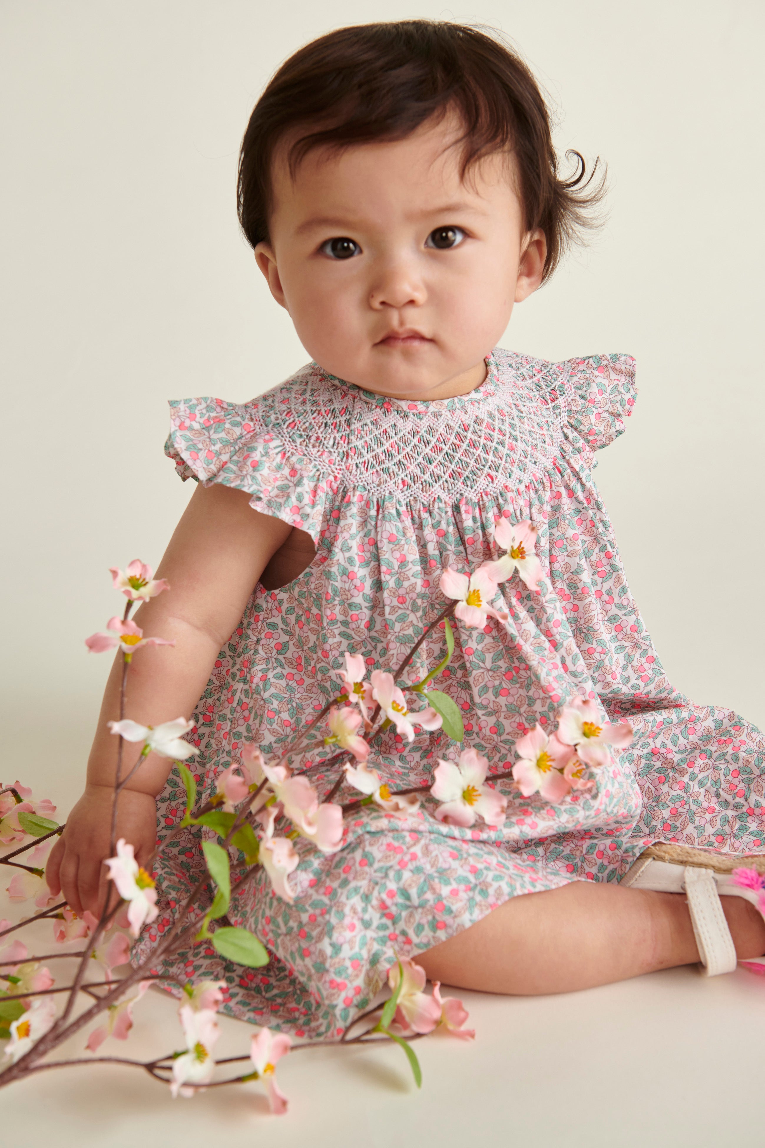 baby model sitting in hand-smoked Liberty print frill dress, closeup