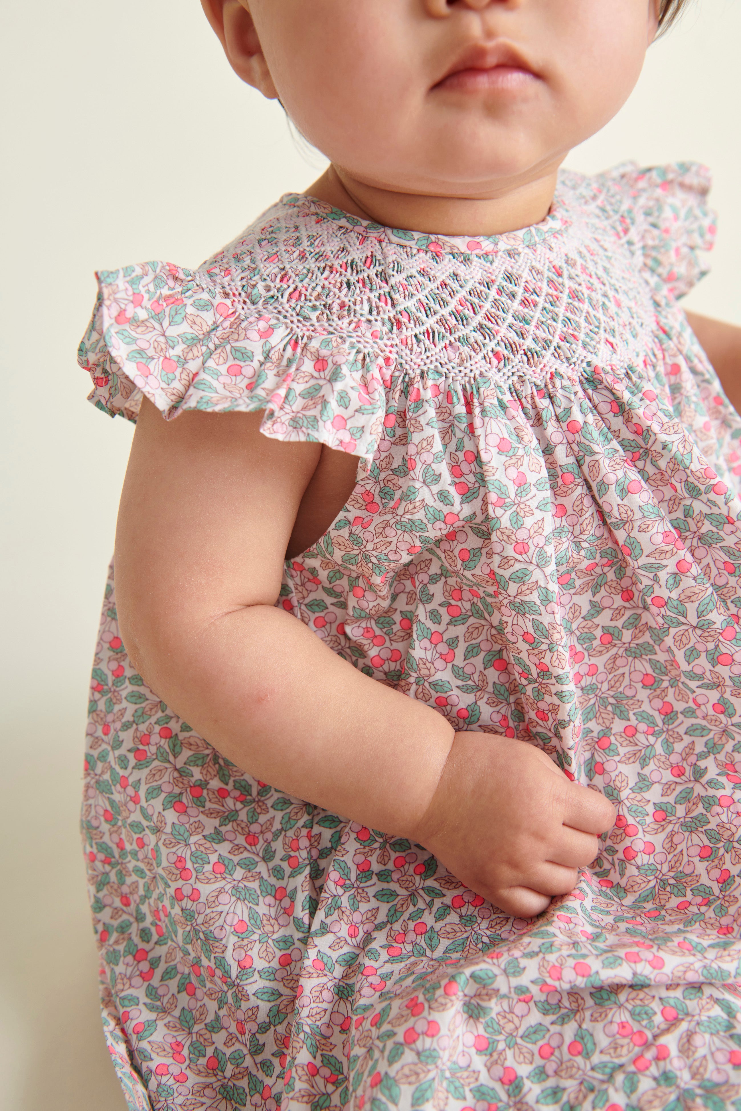 baby model sitting in hand-smoked Liberty print frill dress, smocking detail shot