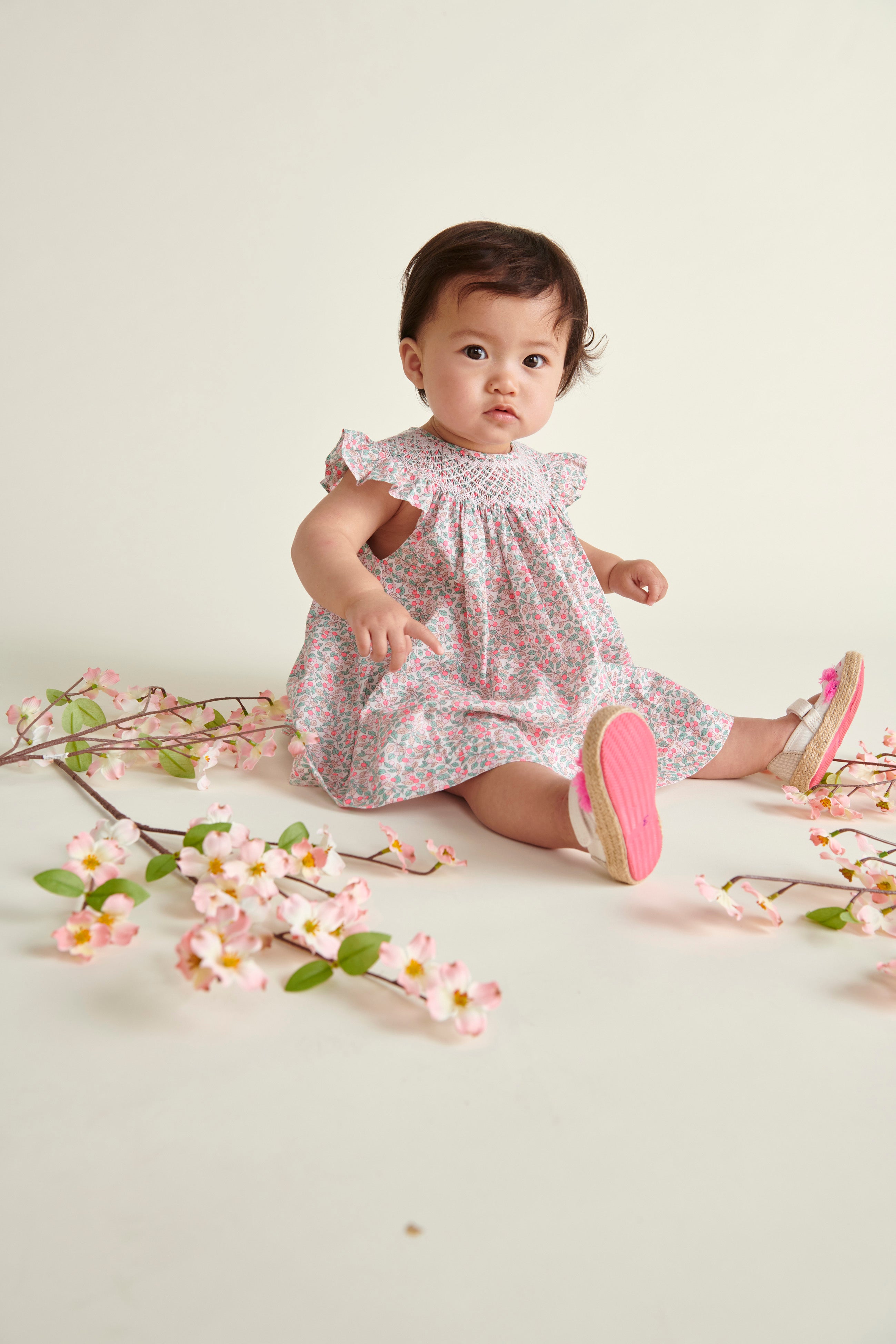 baby model sitting in hand-smoked Liberty print frill dress