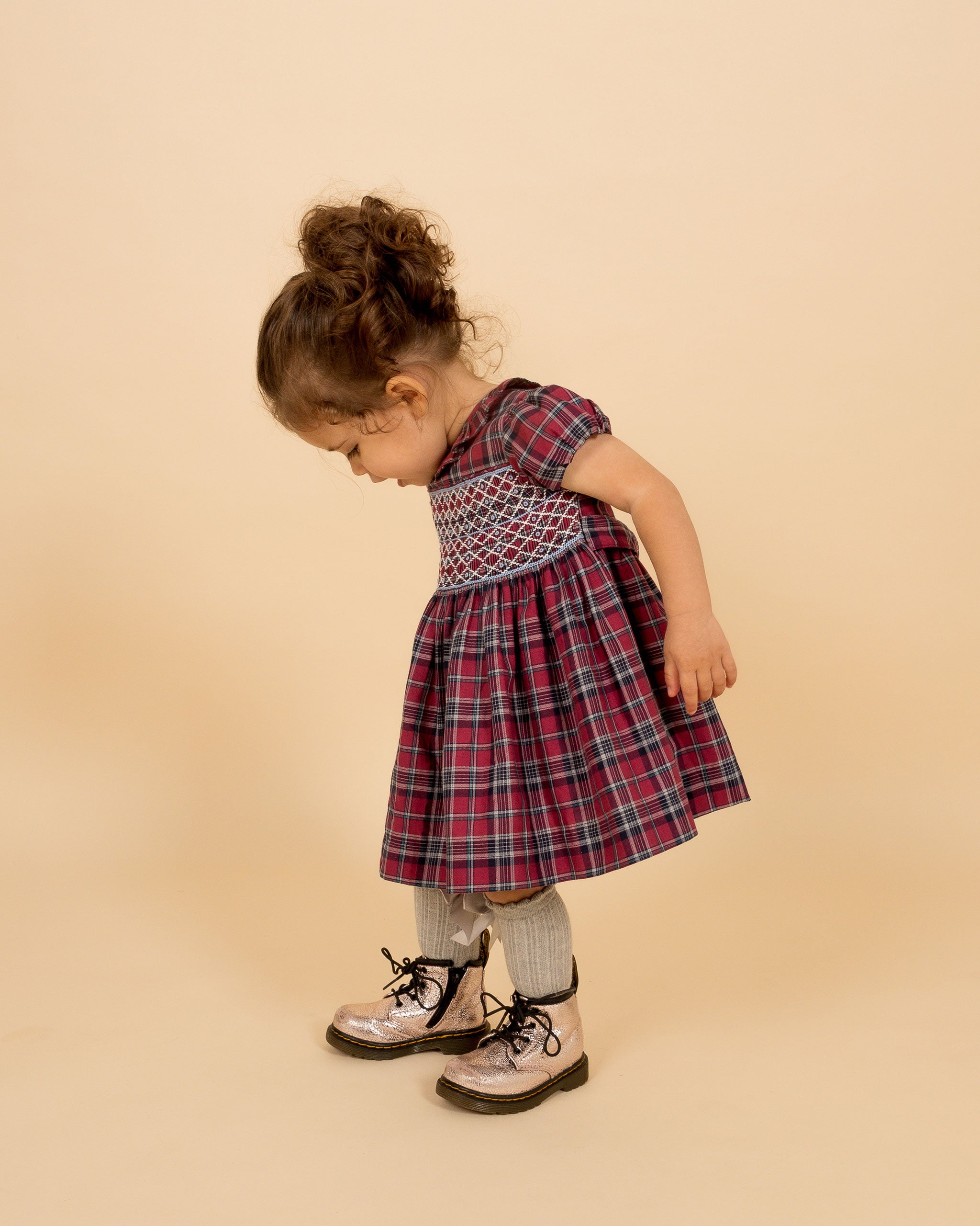 toddler wearing smocked tartan dress and baby metallic DM's