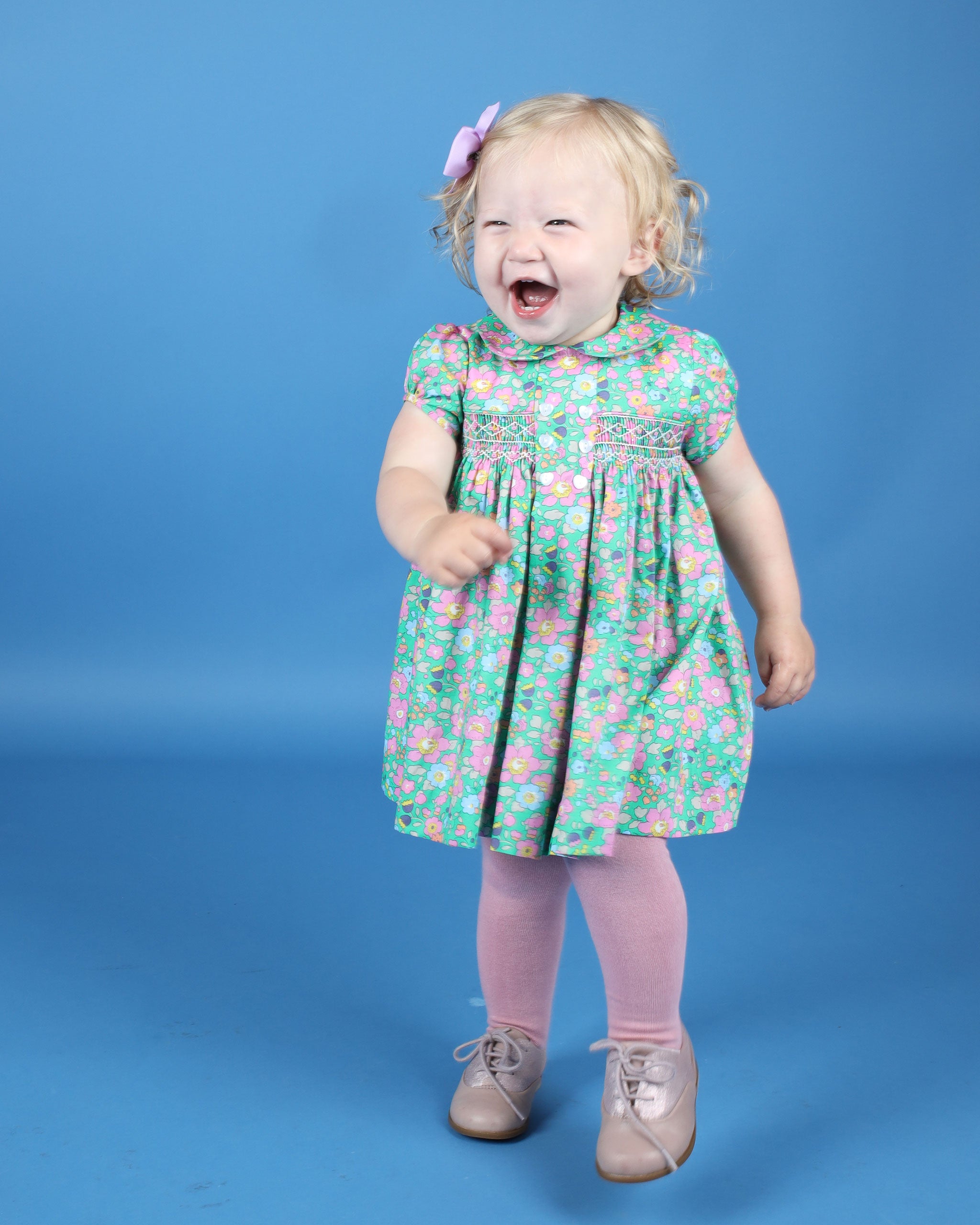 Baby in green floral hand-smocked dress made from Liberty fabric.
