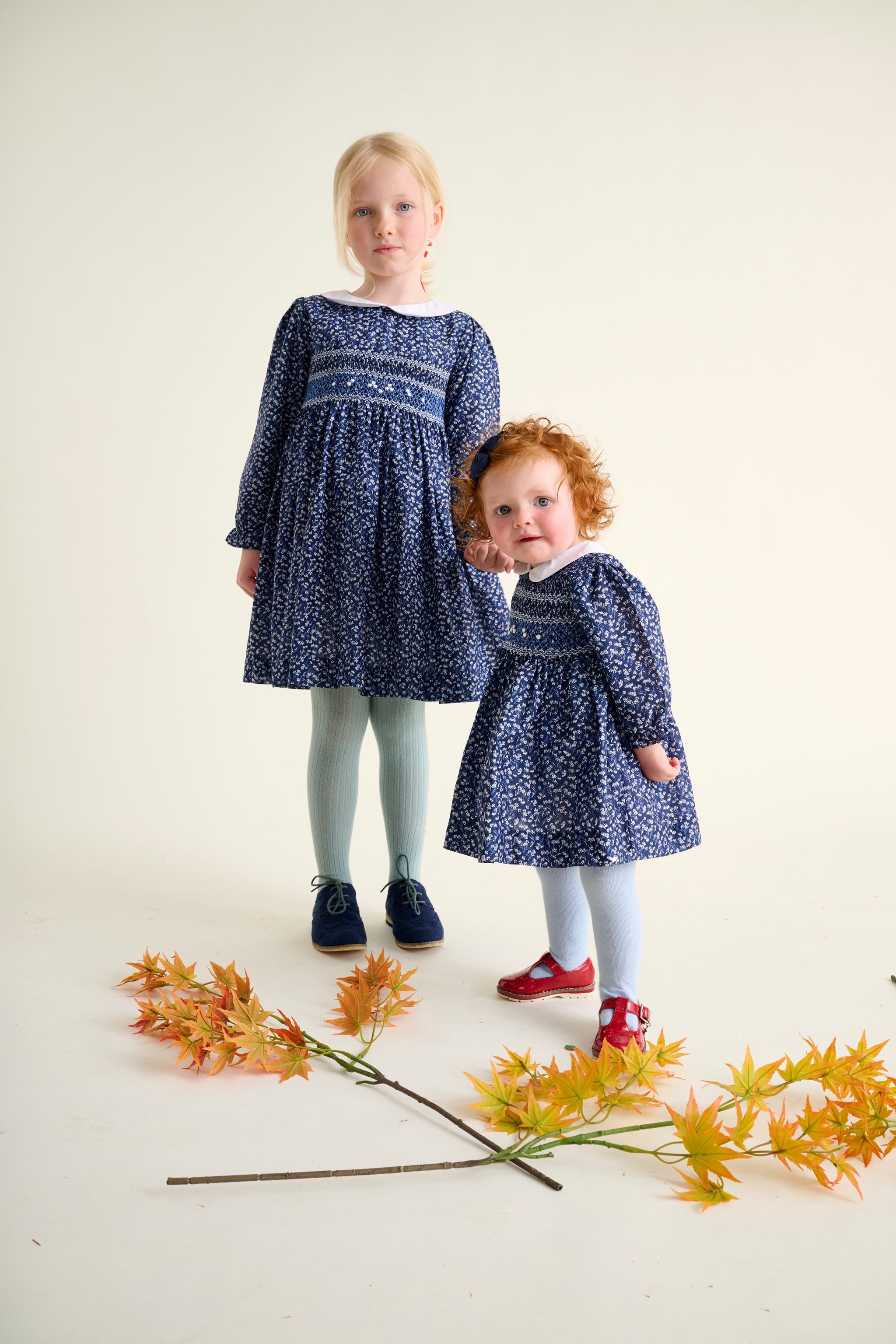 sisters wearing matching blue hand-smocked dresses holding hands