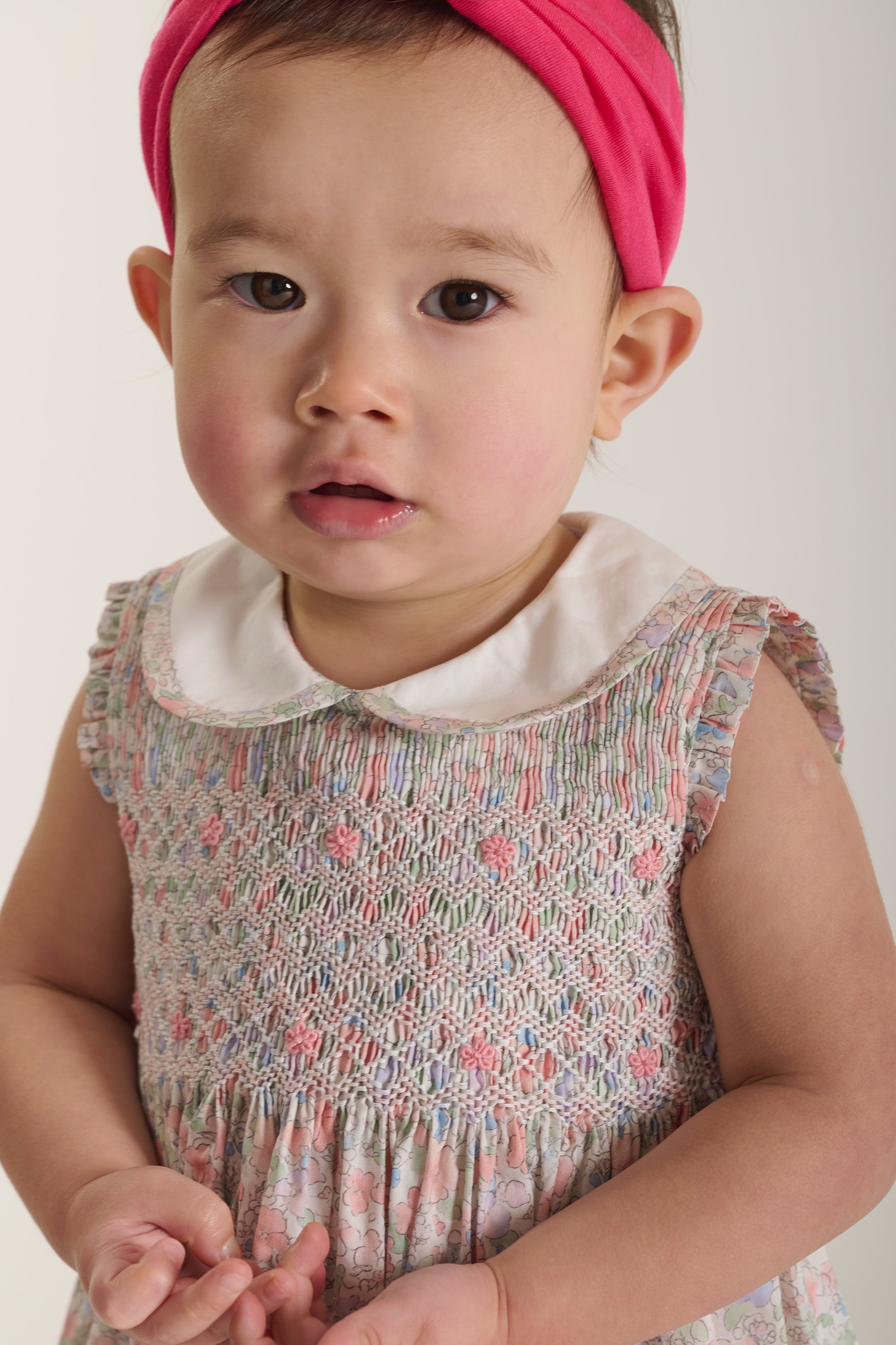 Baby wearing a pastel floral dress with a white collar