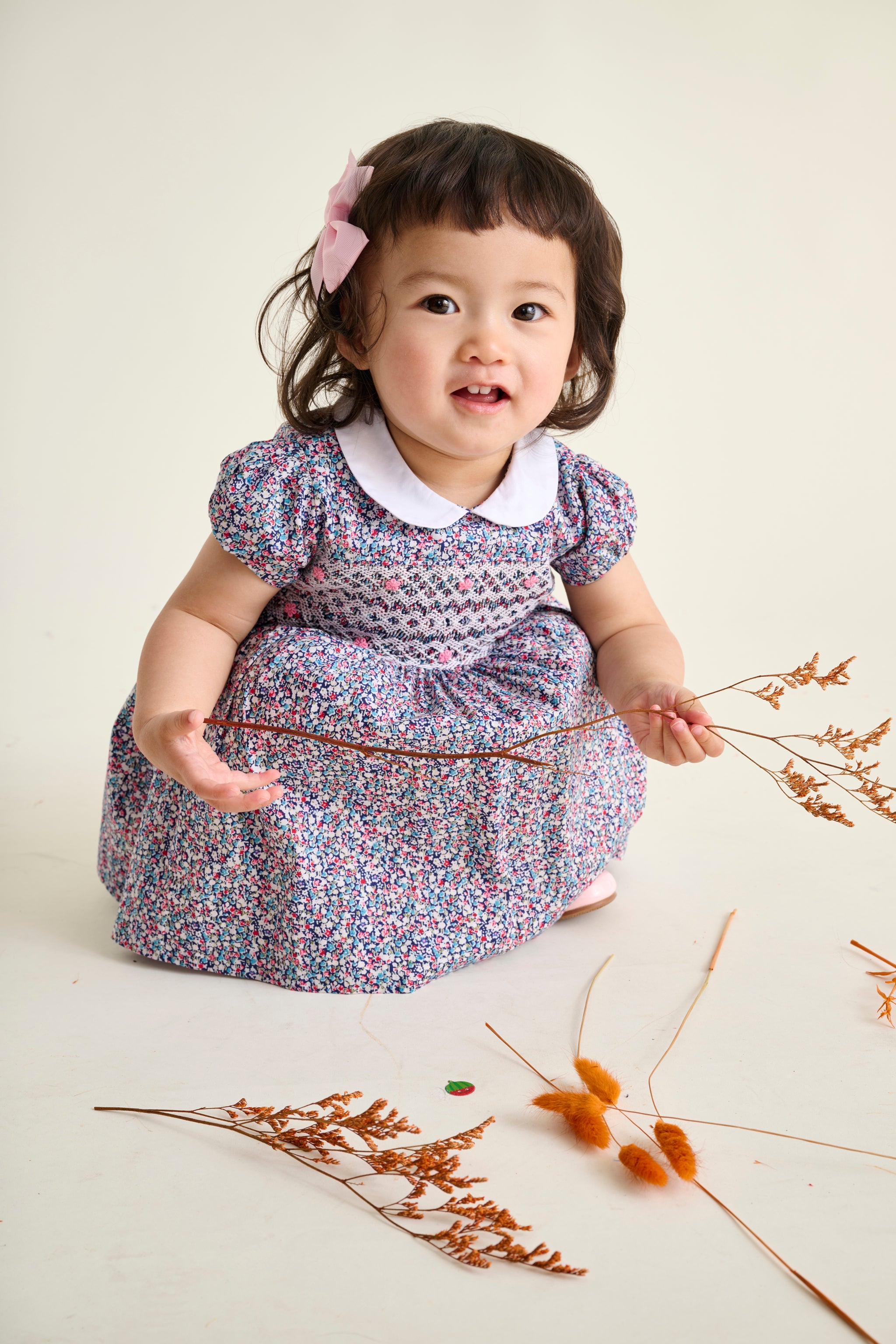 baby kneeling in a hand-smocked floral dress