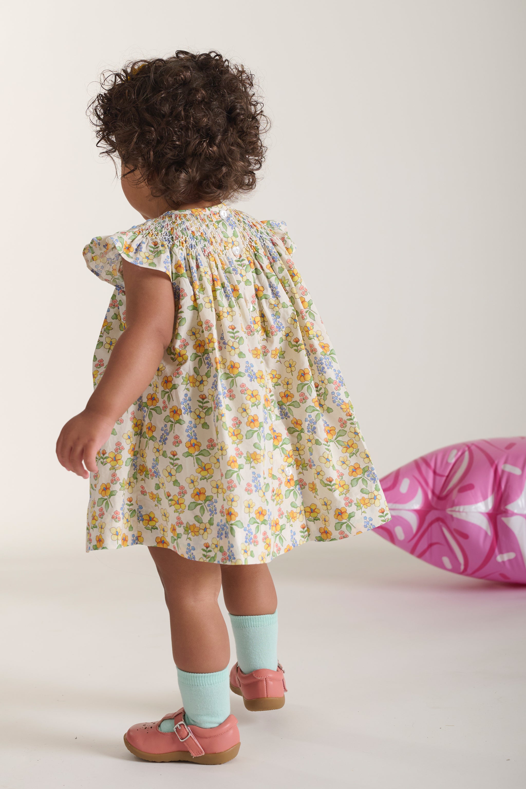 back view of girl in yellow floral smock dress