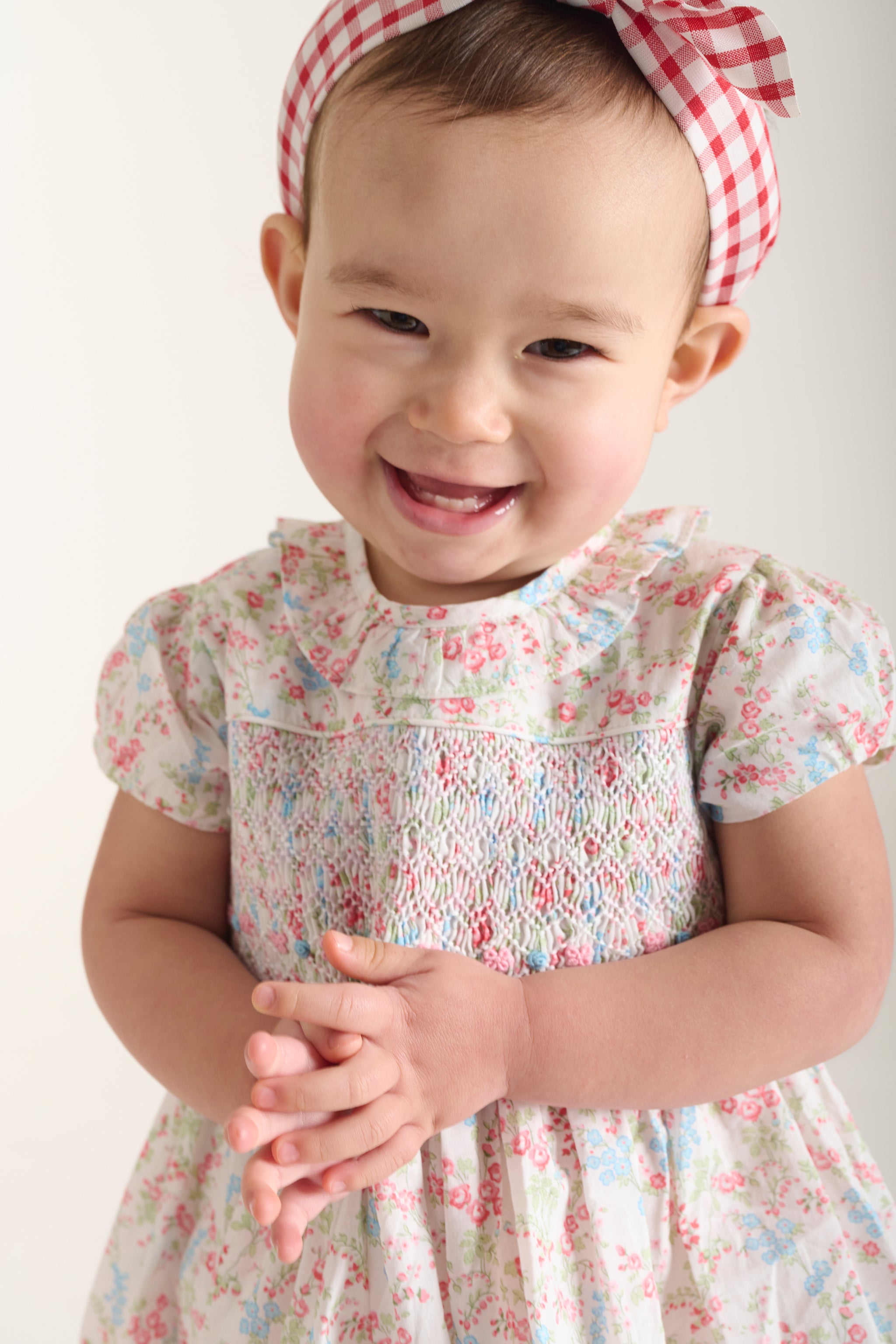 baby wearing a floral summer dress with puff sleeves and hand-smocking