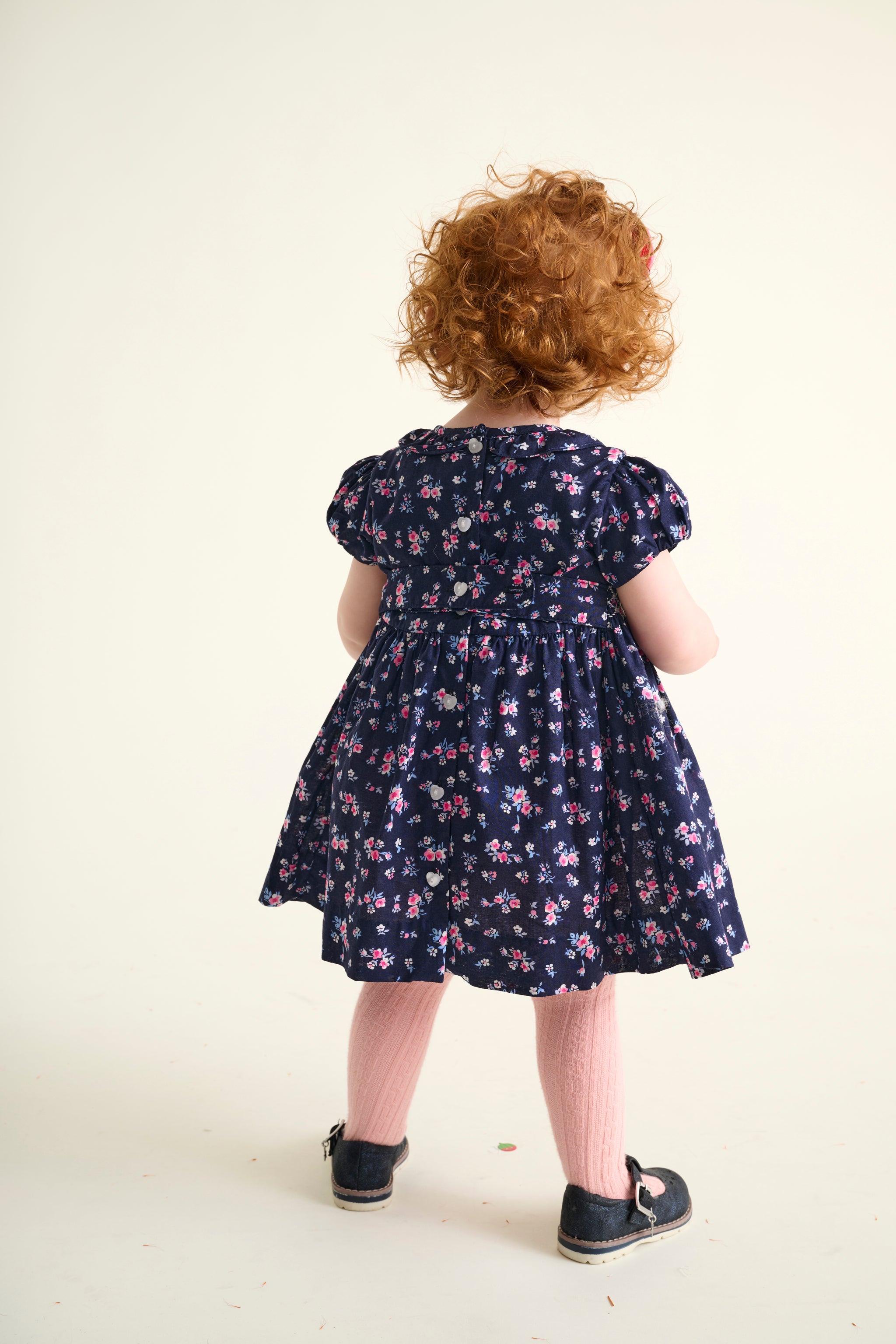 Child wearing a navy floral dress seen from behind