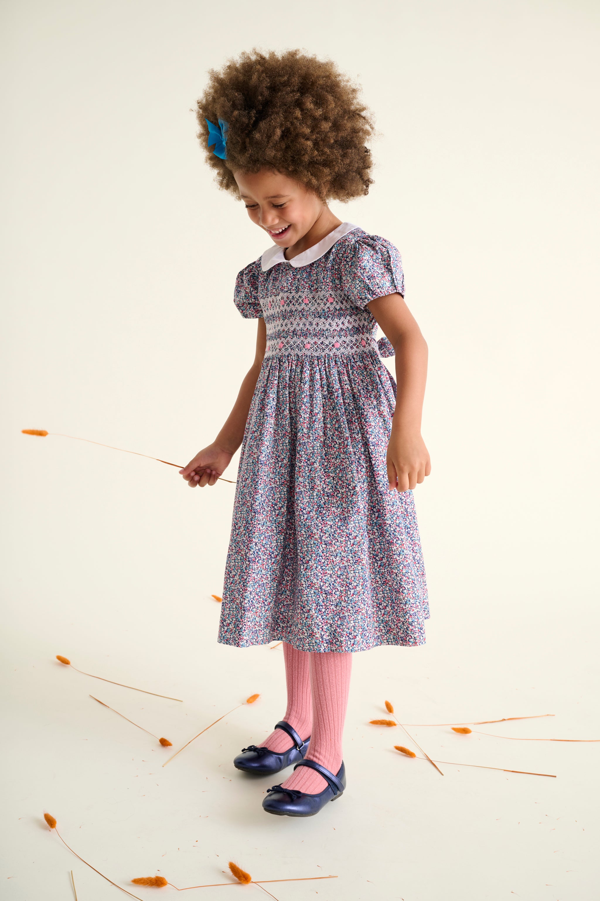 girl in a hand-smoked ditsy floral dress standing on a white background