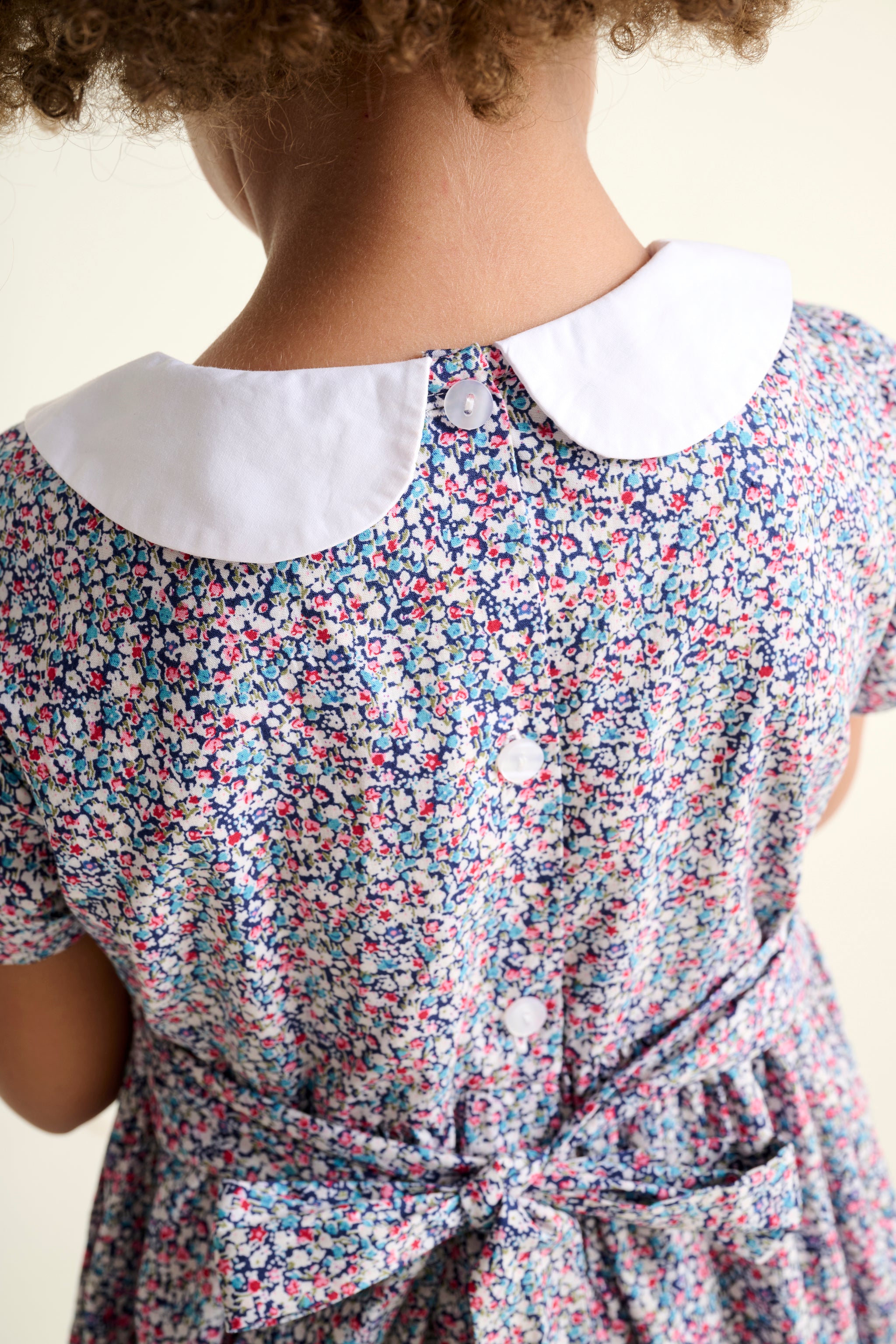 Child wearing a floral dress with a white collar close up