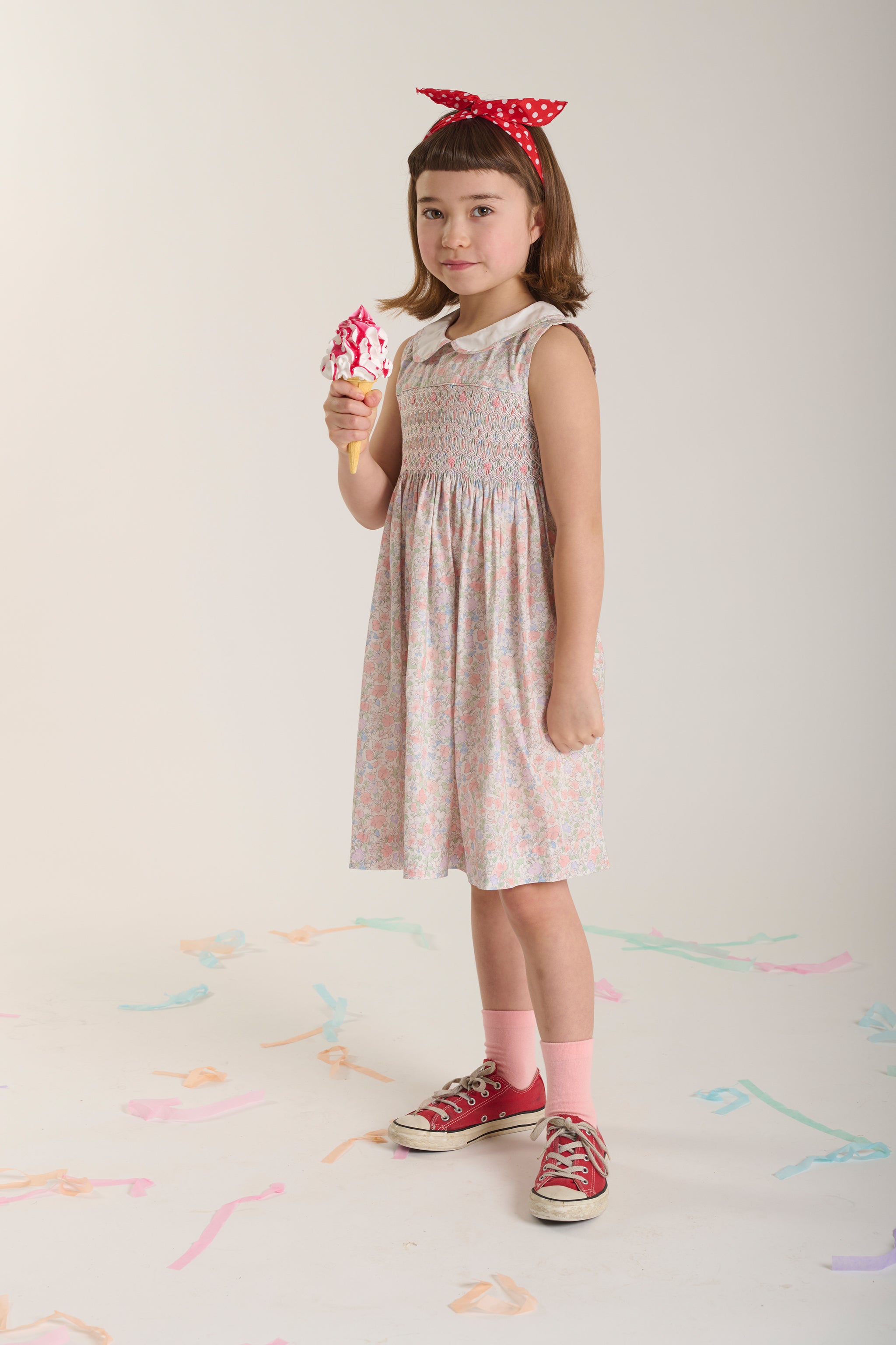 Young girl in a pastel hand-smocked dress holding an ice cream