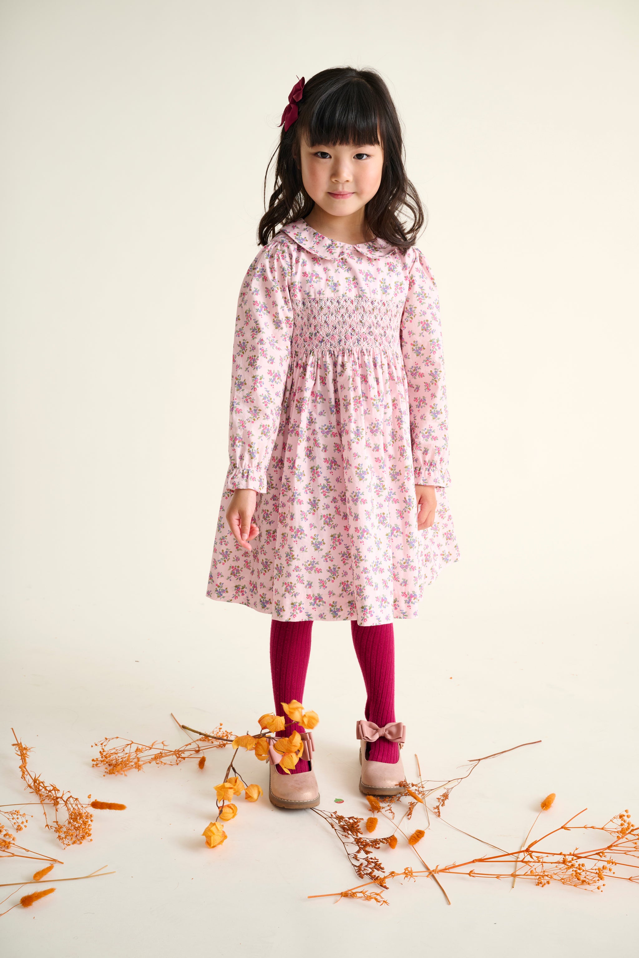 girl wearing a pink floral dress with smocking and embroidery