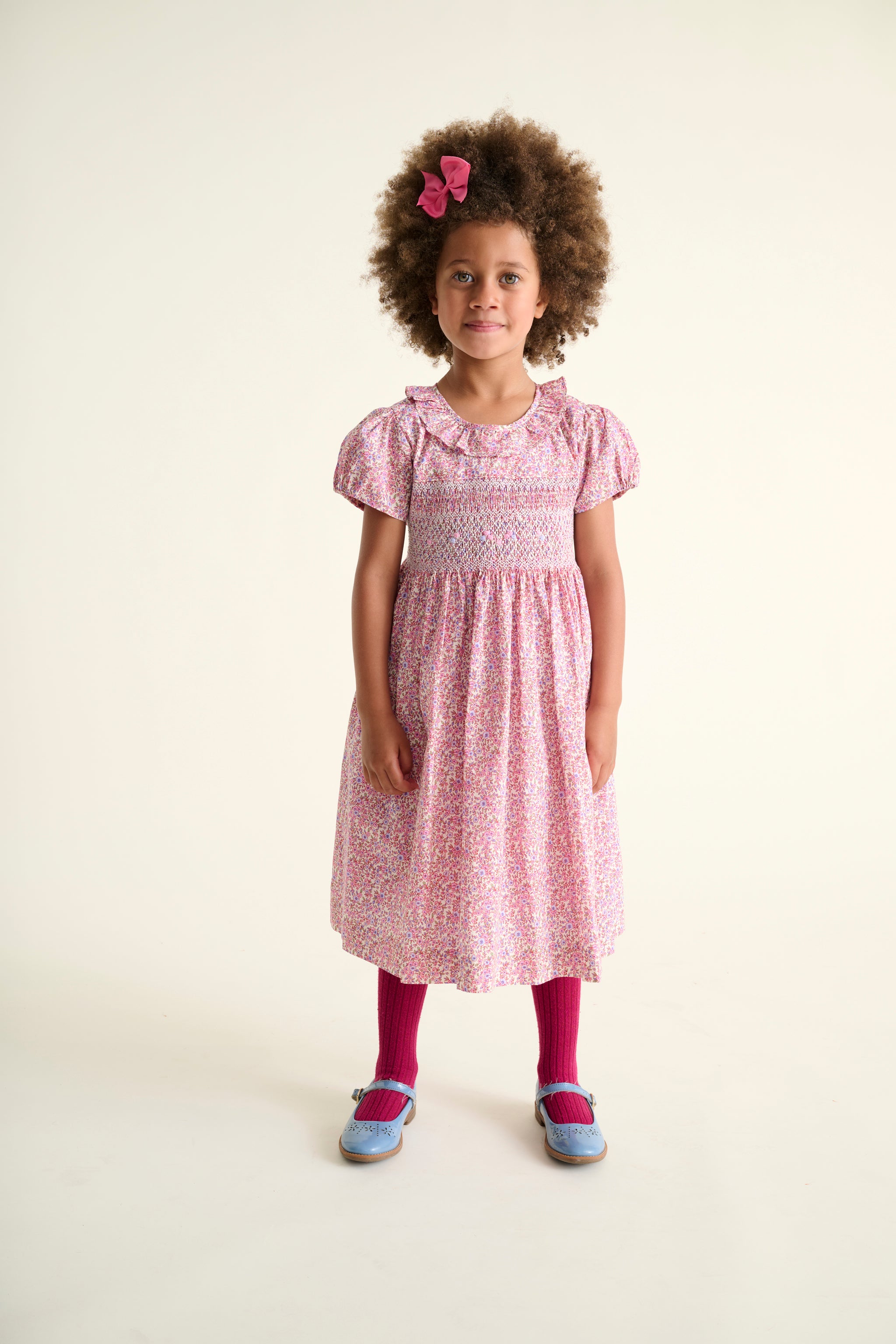 Girl wearing a pink dress with frill collar and hand smocking