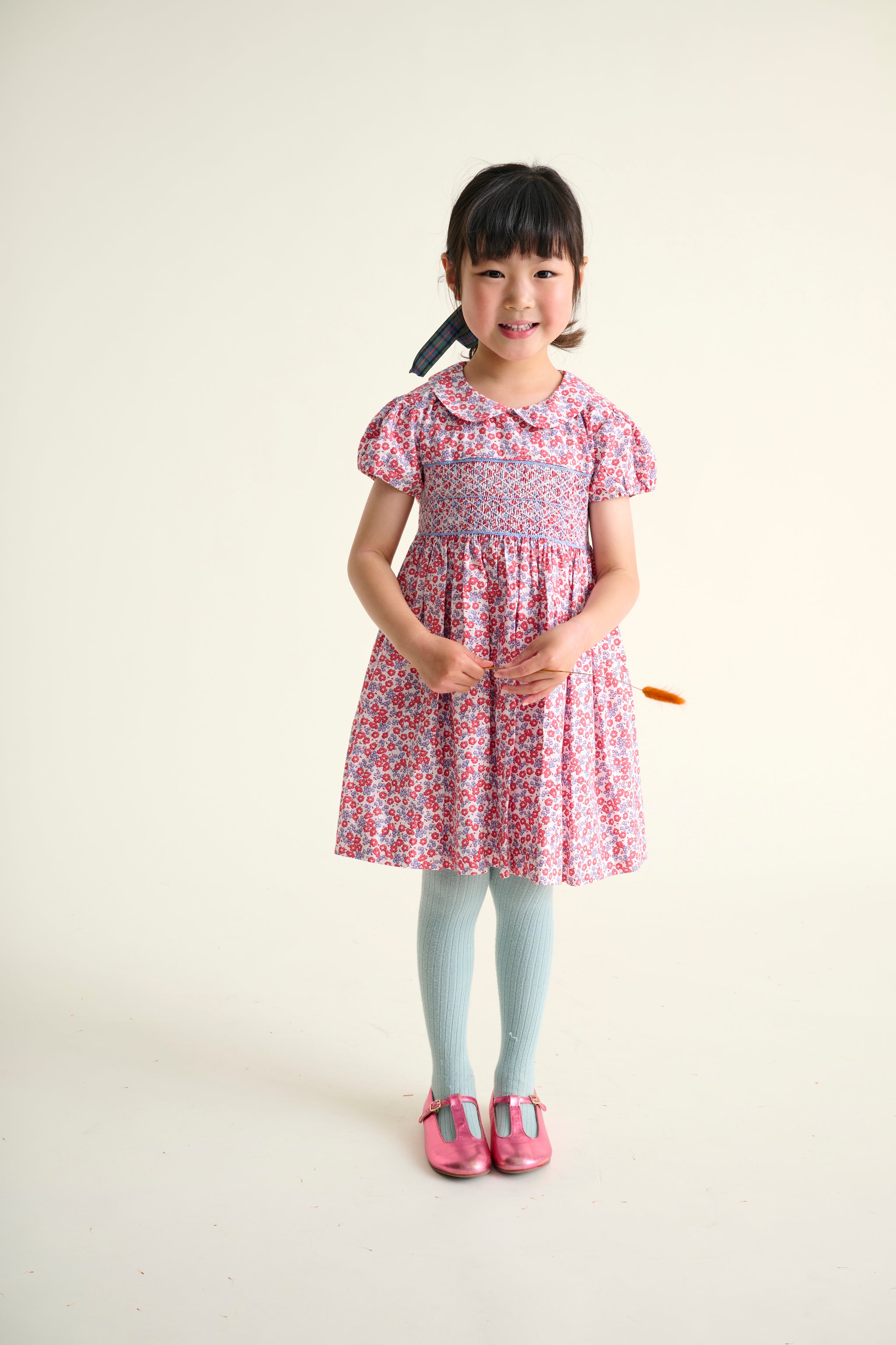Girl wearing a red and blue floral dress on a white background