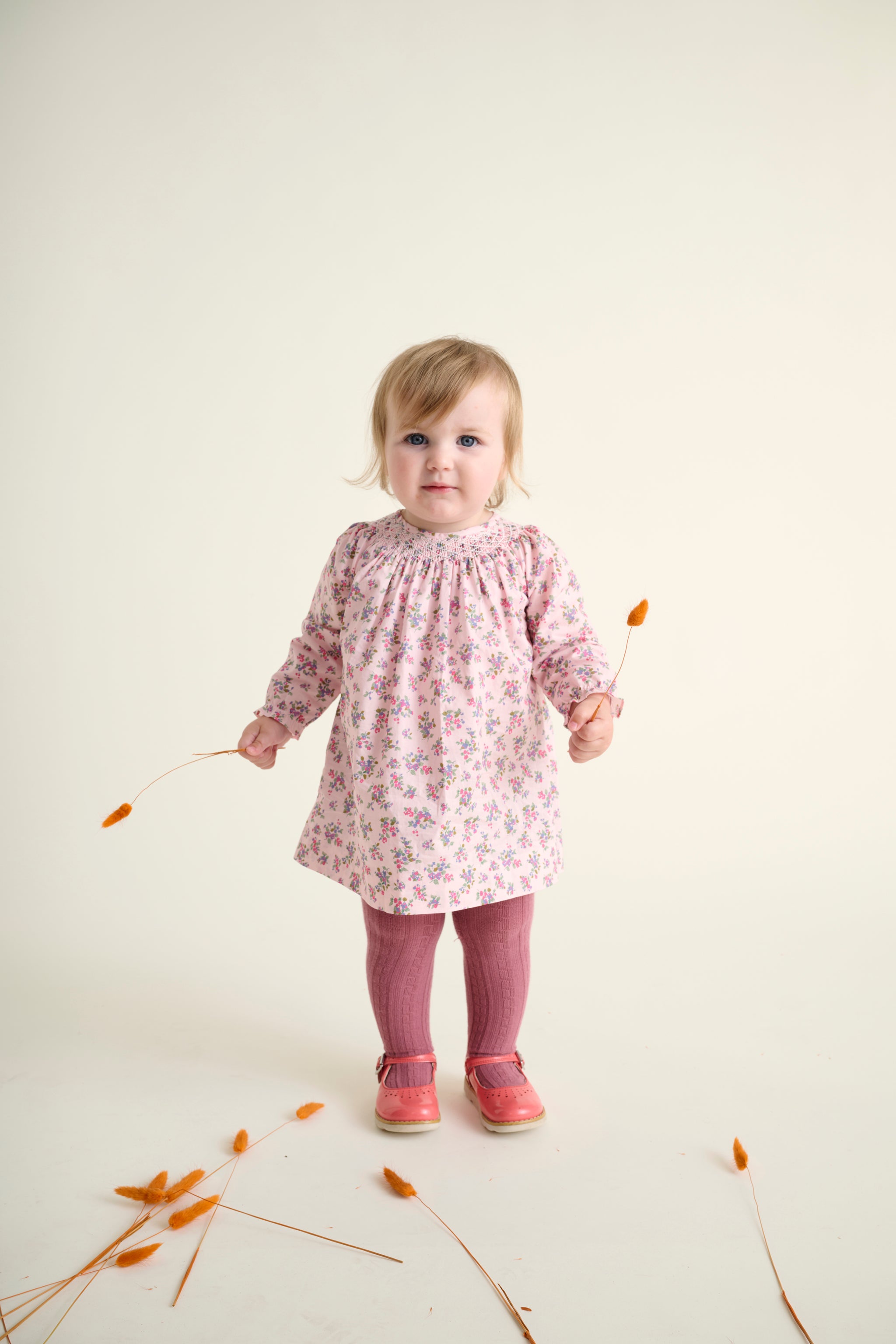 toddler girls wearing a pink floral dress with long sleeves and hand-smocked neckline