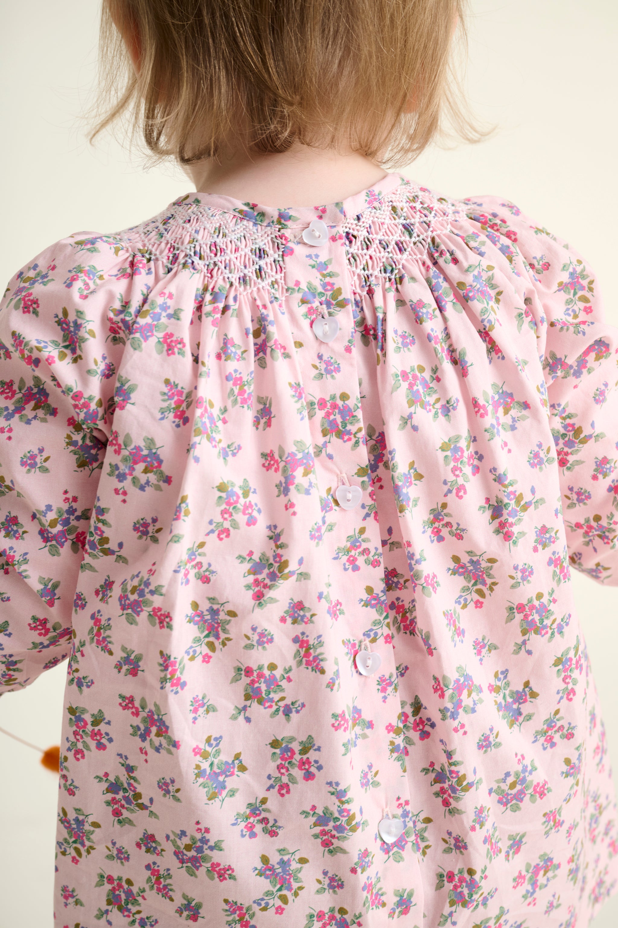 Child wearing a floral dress with a white background