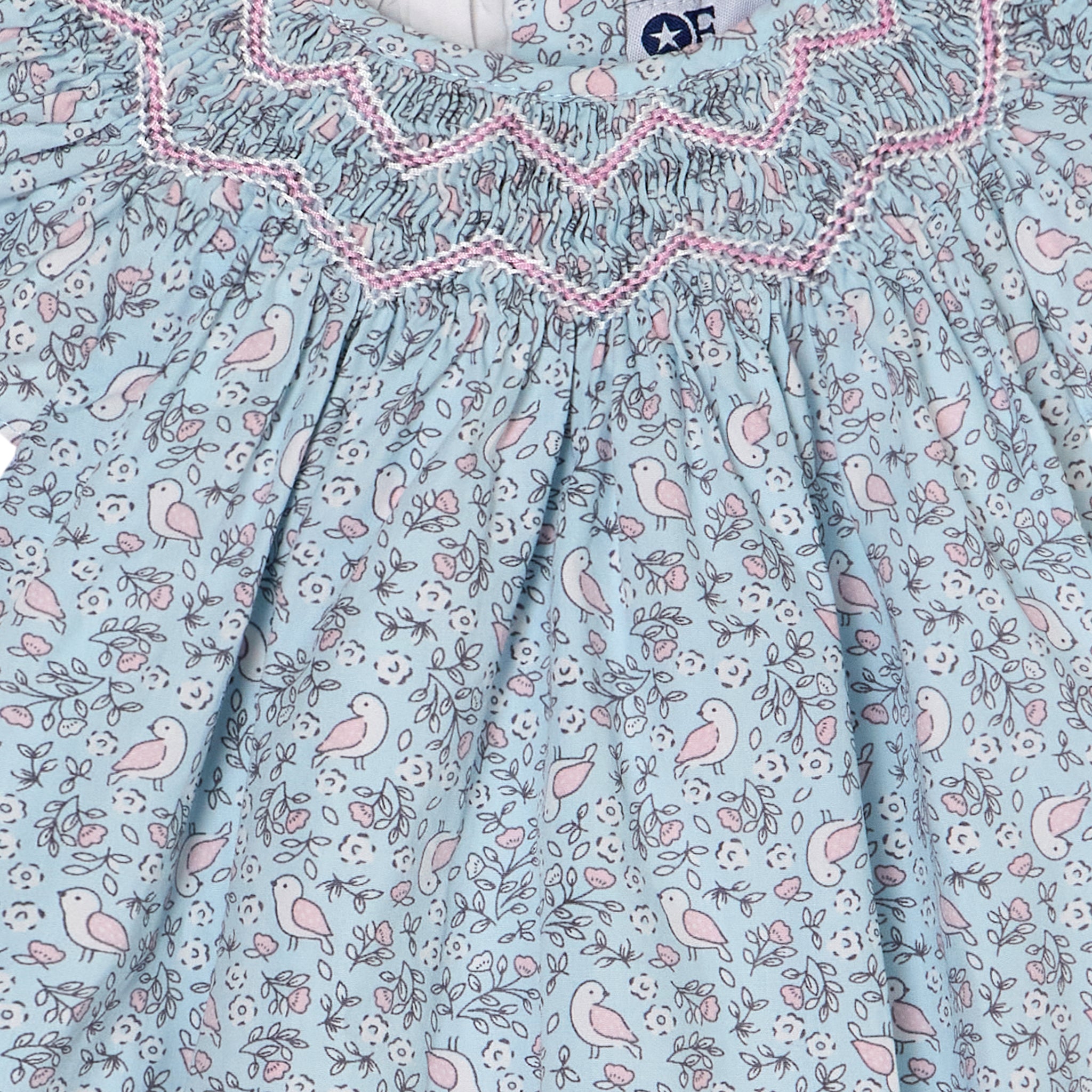 Light blue romper with pink and white bird pattern and ruffled neckline