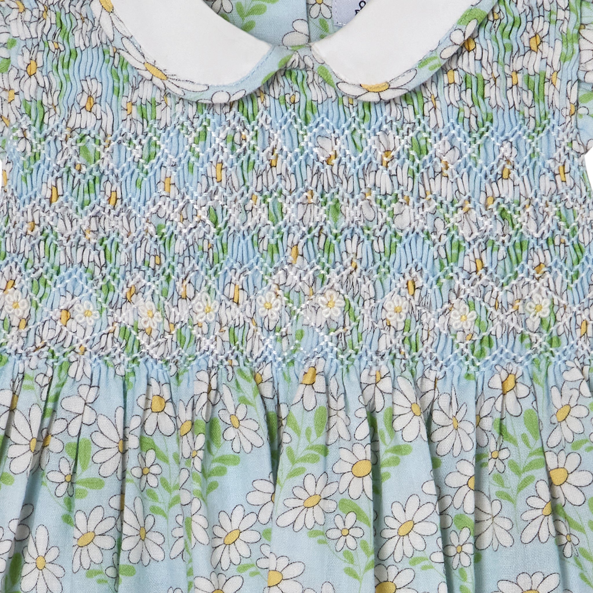 Smocked floral dress with daisy pattern on a light blue background