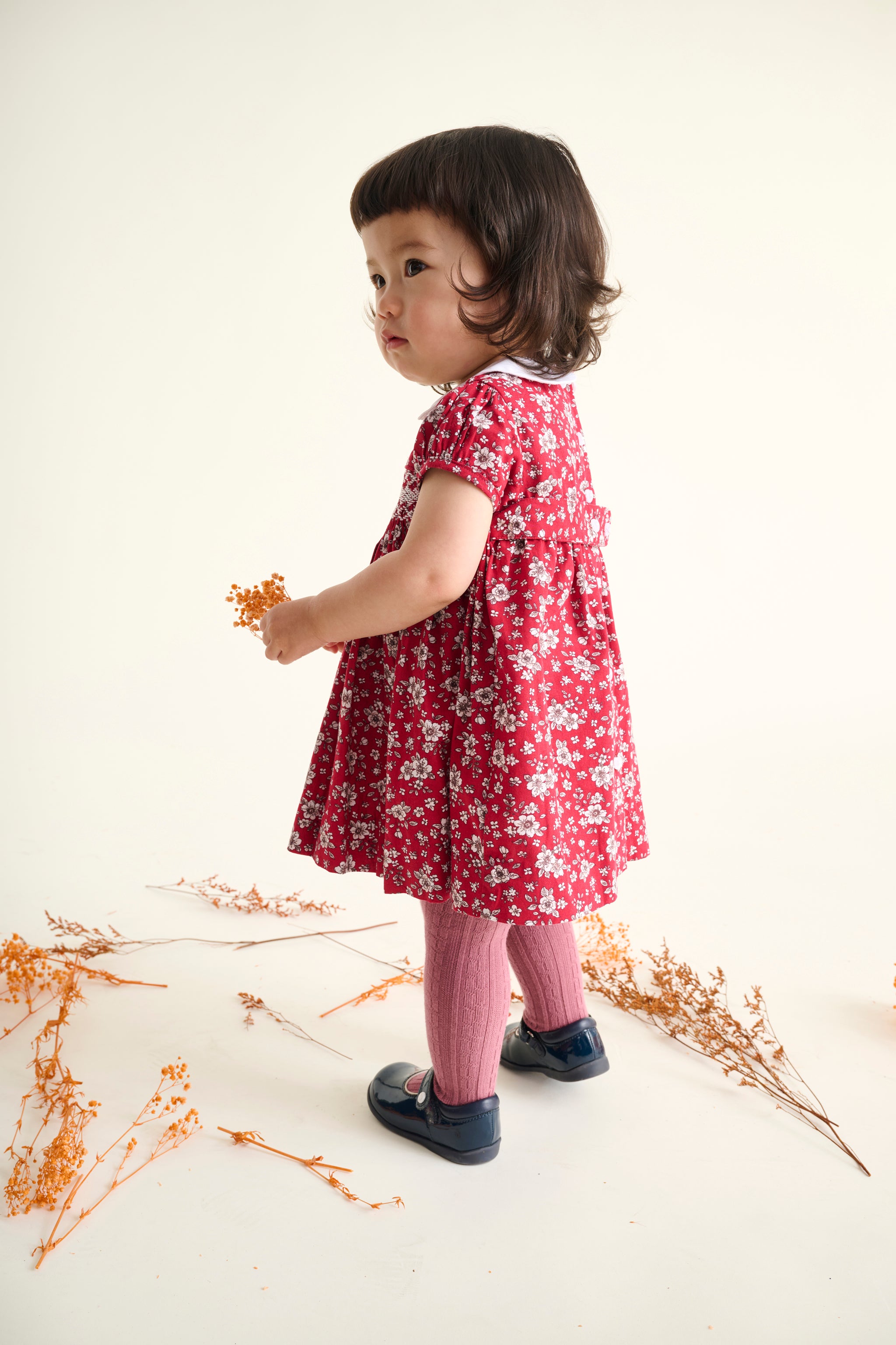 baby girl in a red floral dress view from the side