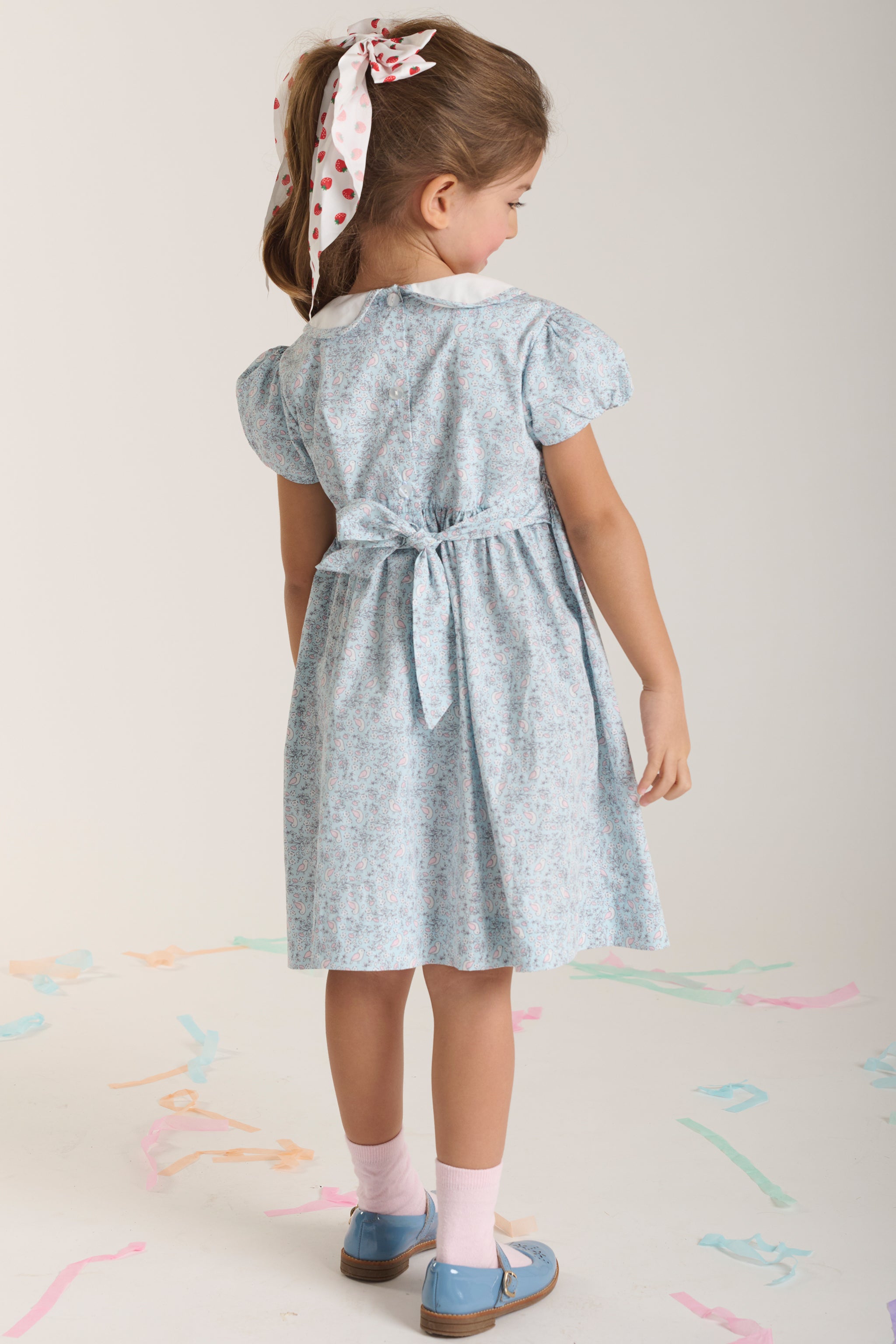 Young girl wearing a blue dress with a back view