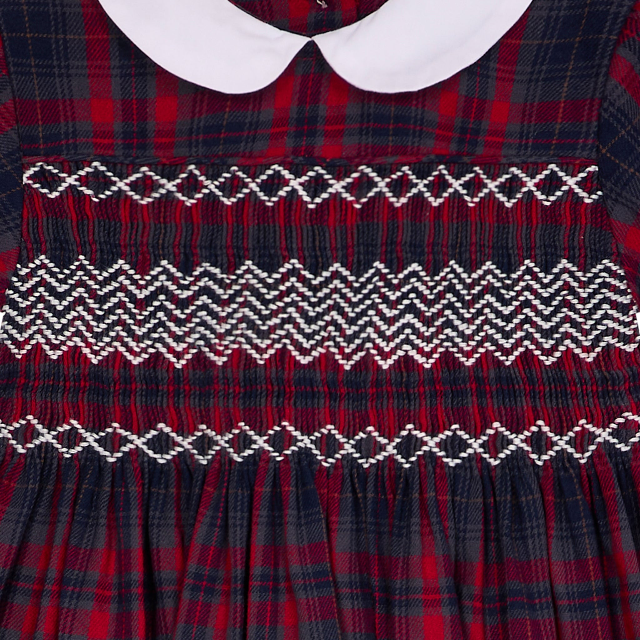 Red and black plaid dress with white collar and intricate smocking detail