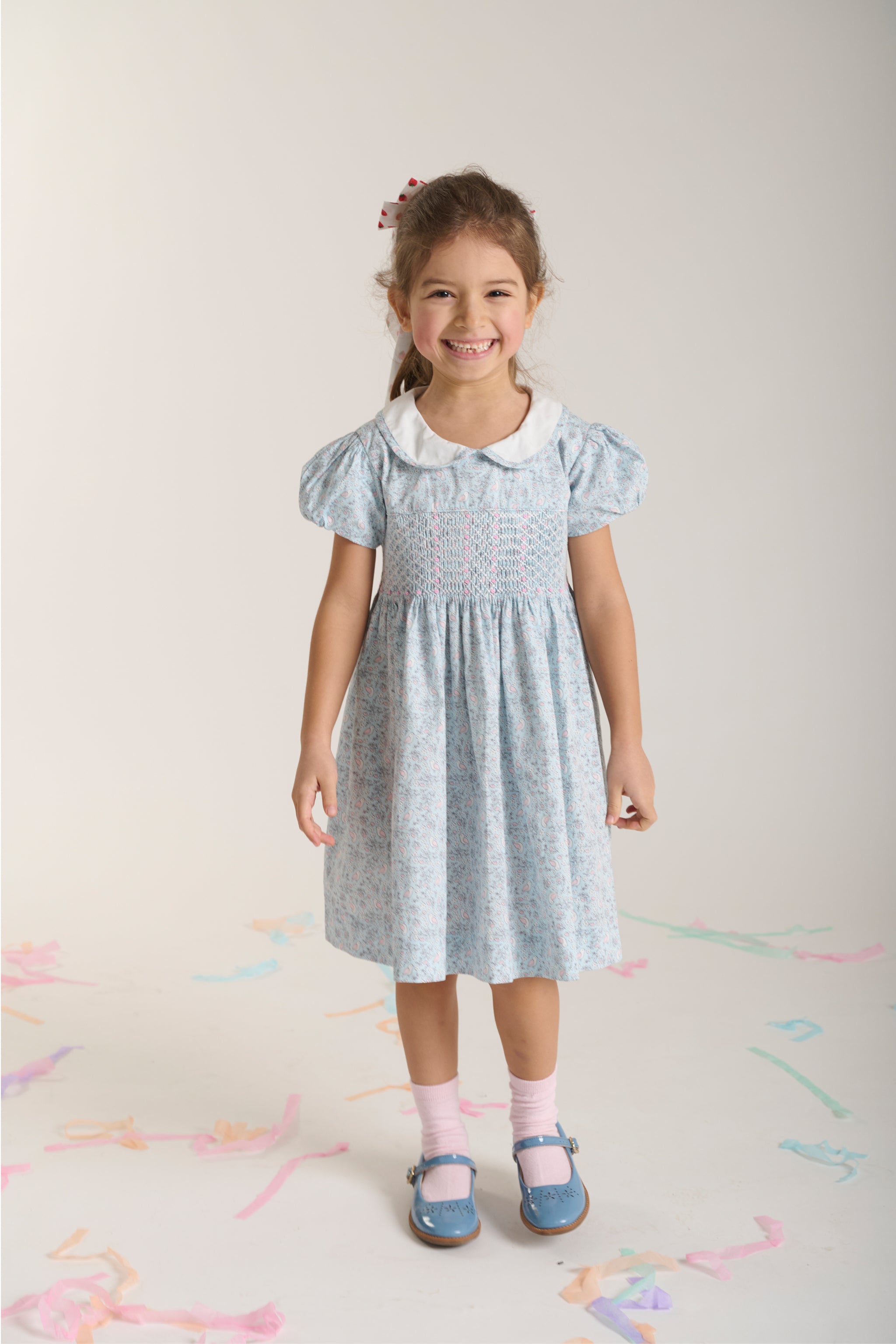 Young girl wearing a light blue bird print dress with puff sleeves and collar