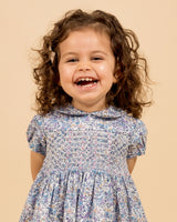 laughing toddler model in Loberty fabric dress, blue, smocked