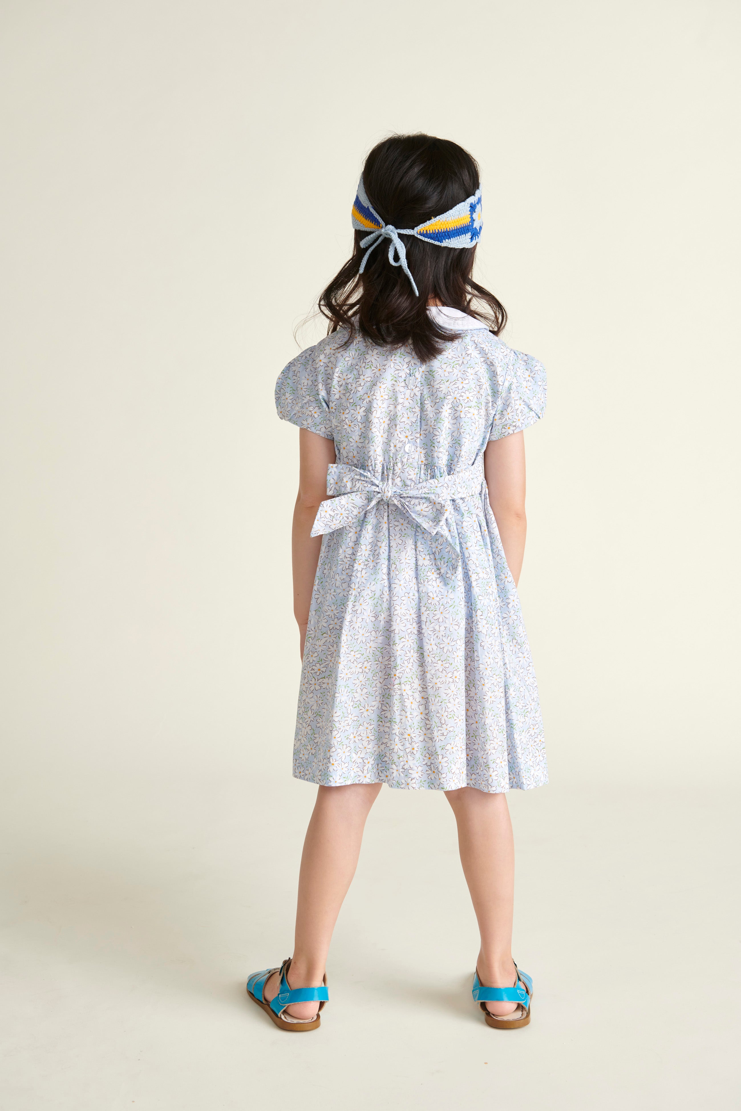 girl in daisy print smocked dress, back view