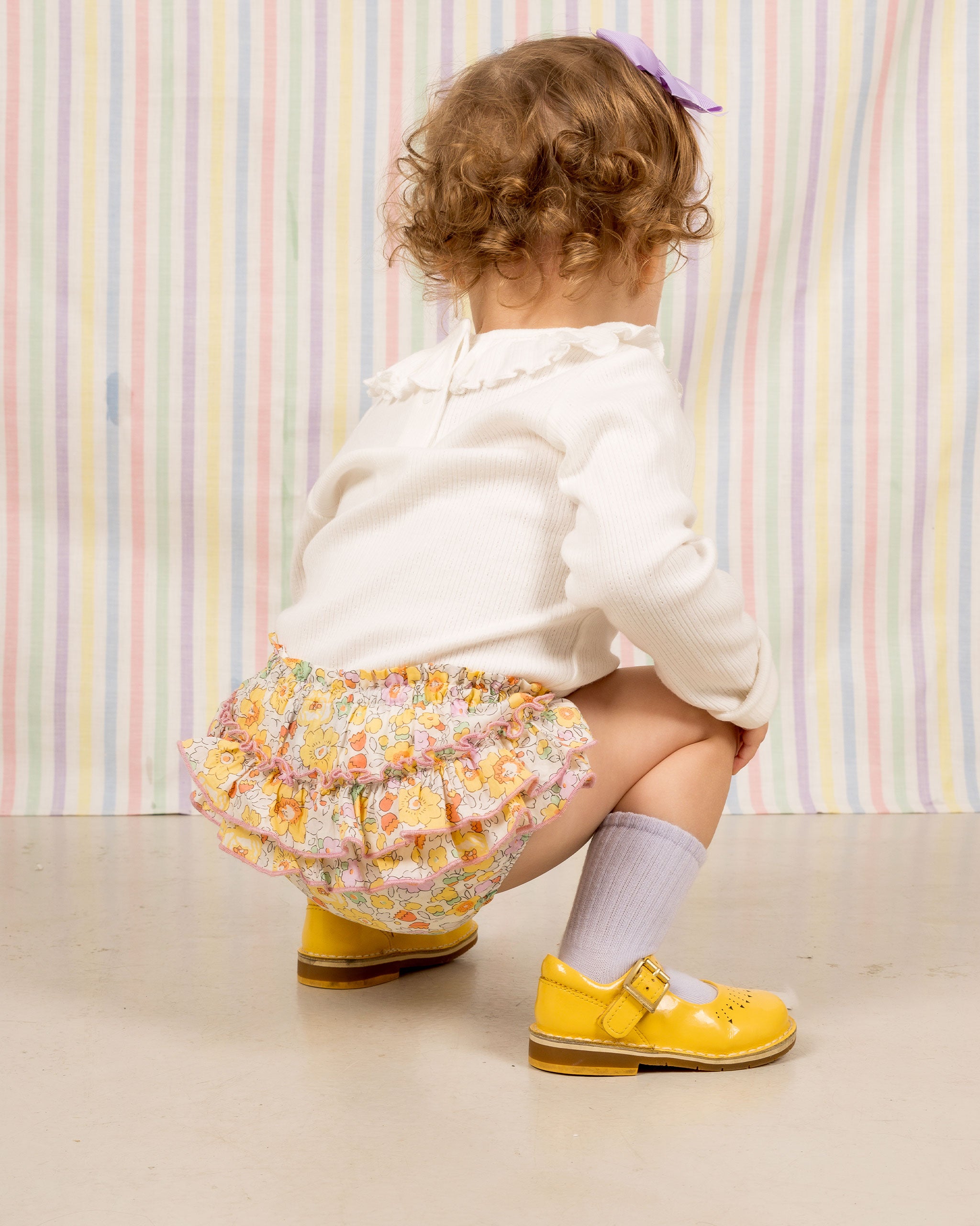 baby crouching in yellow floral bloomer
