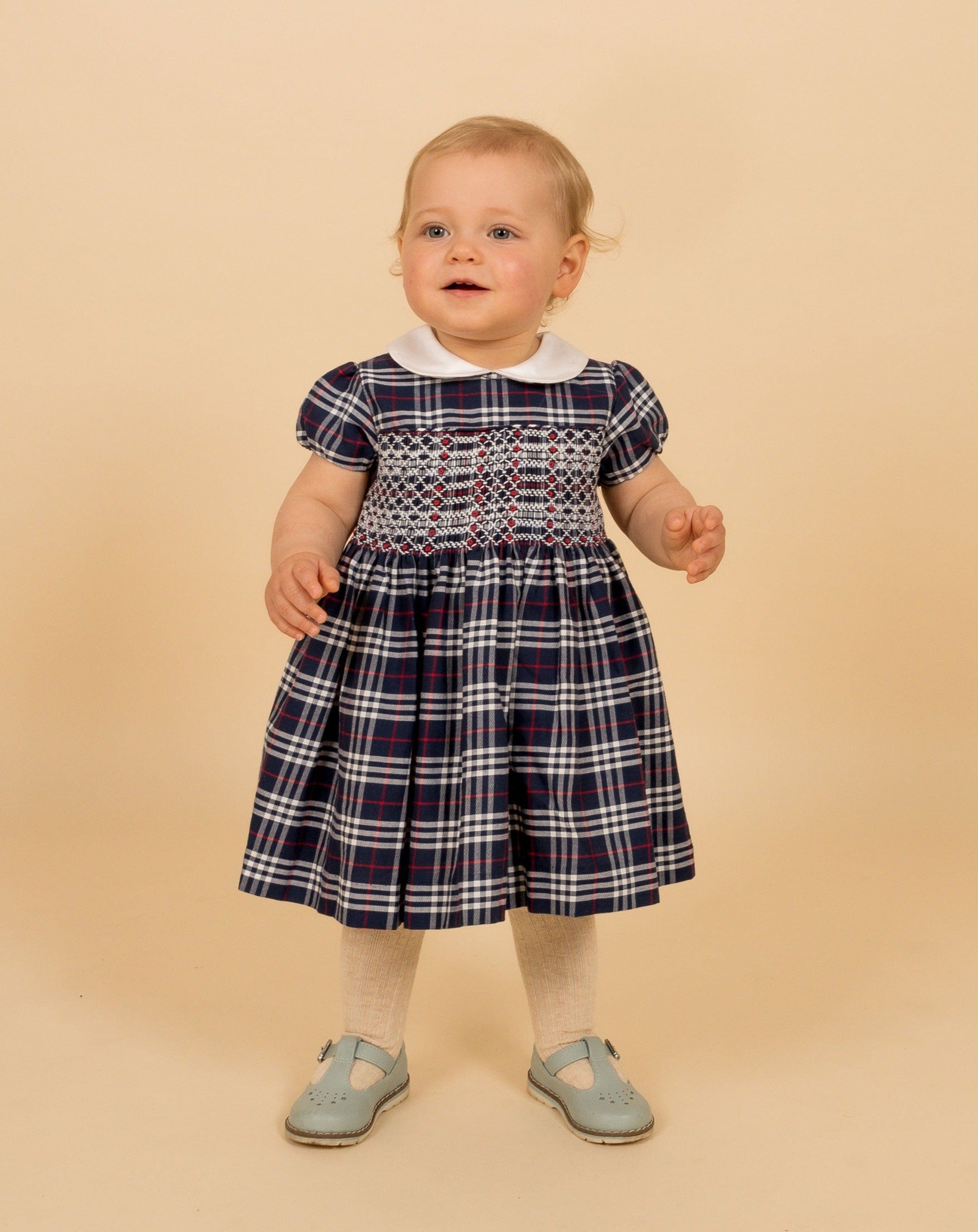 baby in navy smock tartan dress