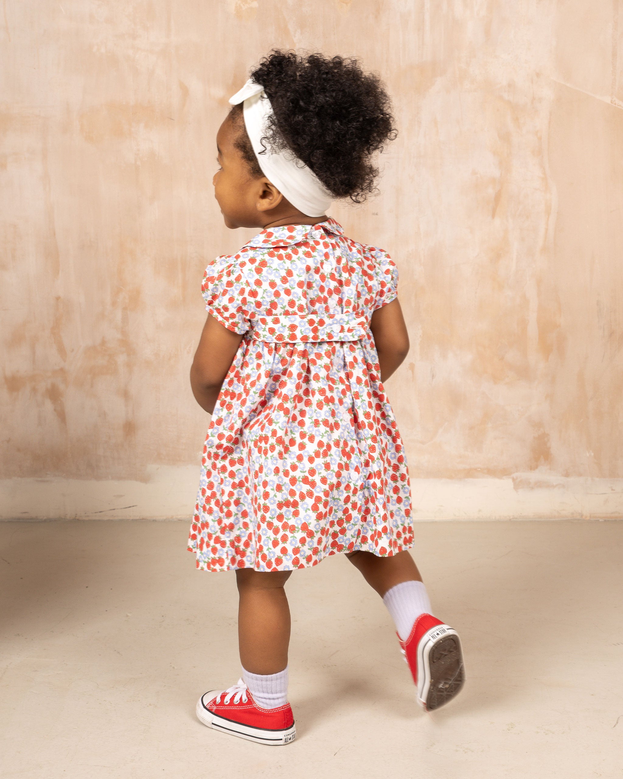 baby girl in strawberry dresss, back view