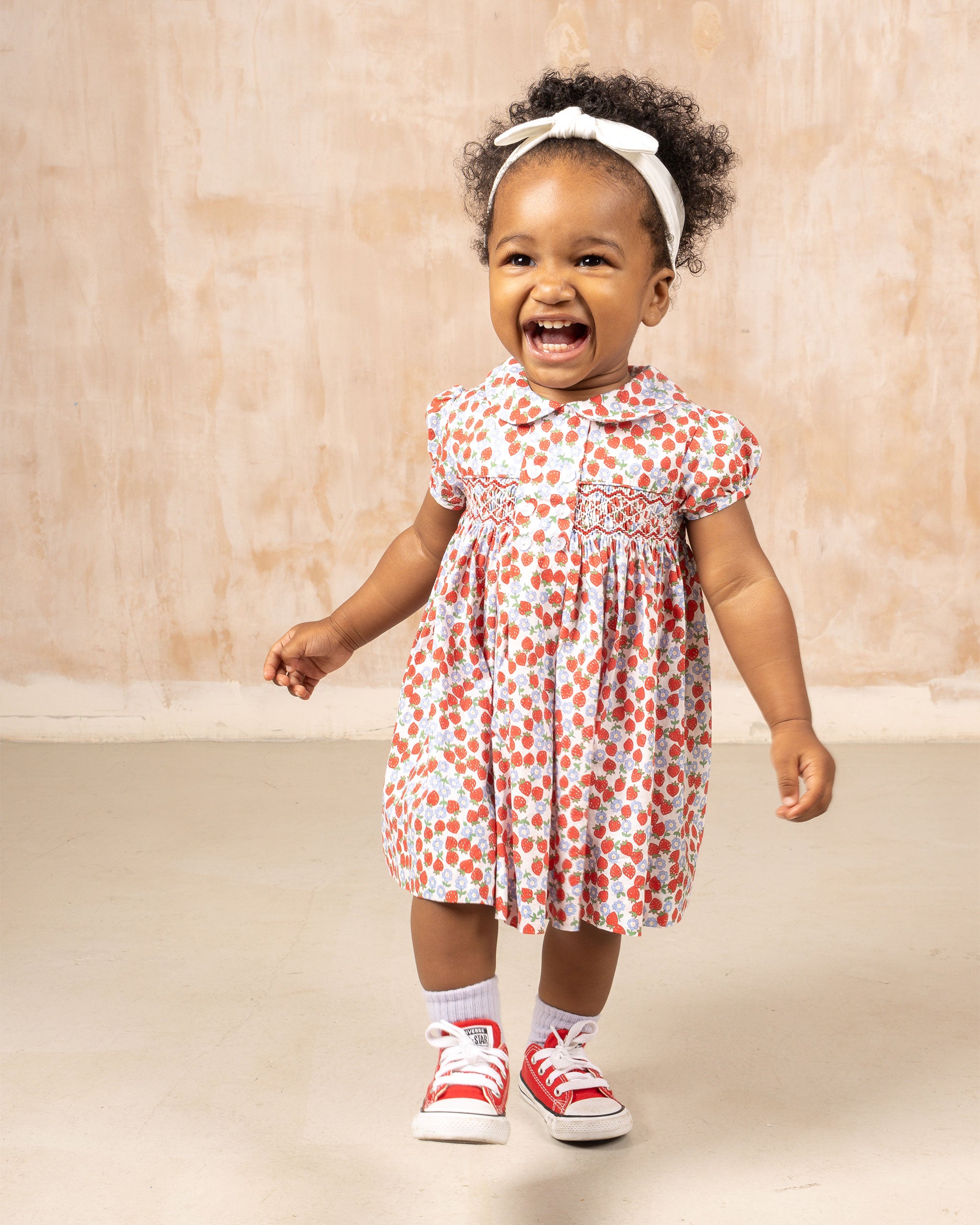 toddler in strawberry print dress.
