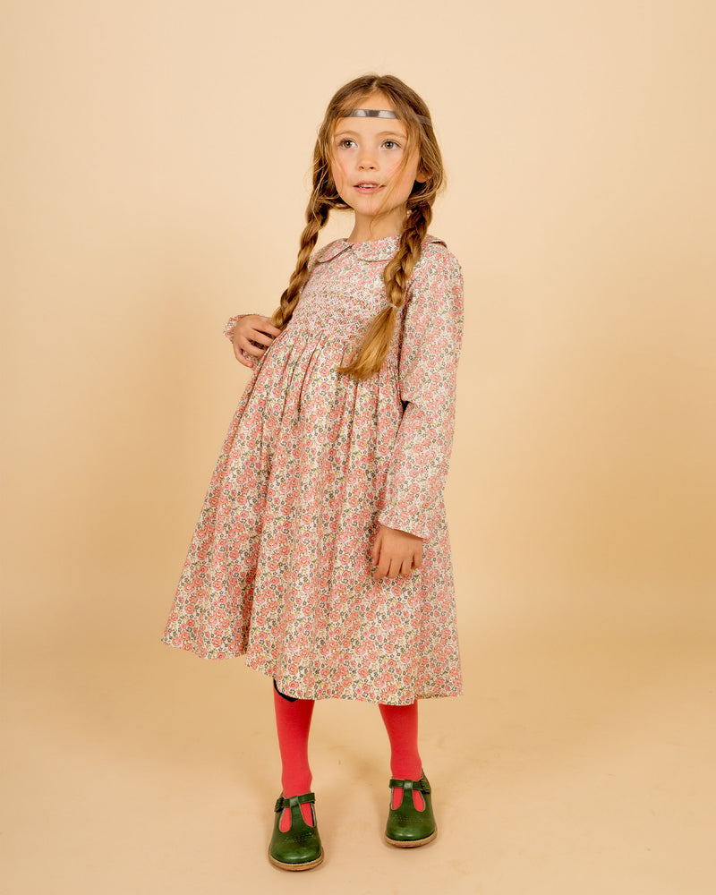 girl wearing pale floral smock dress for winter