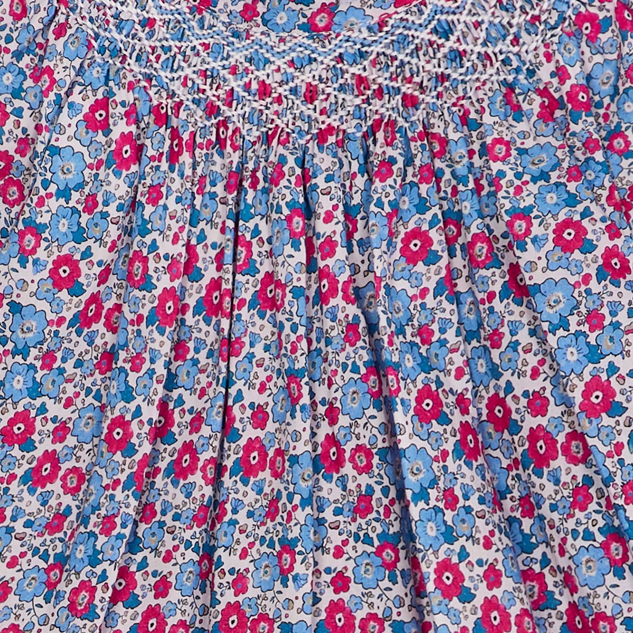 Close-up of a floral patterned fabric with pink and blue flowers with hand-smocking