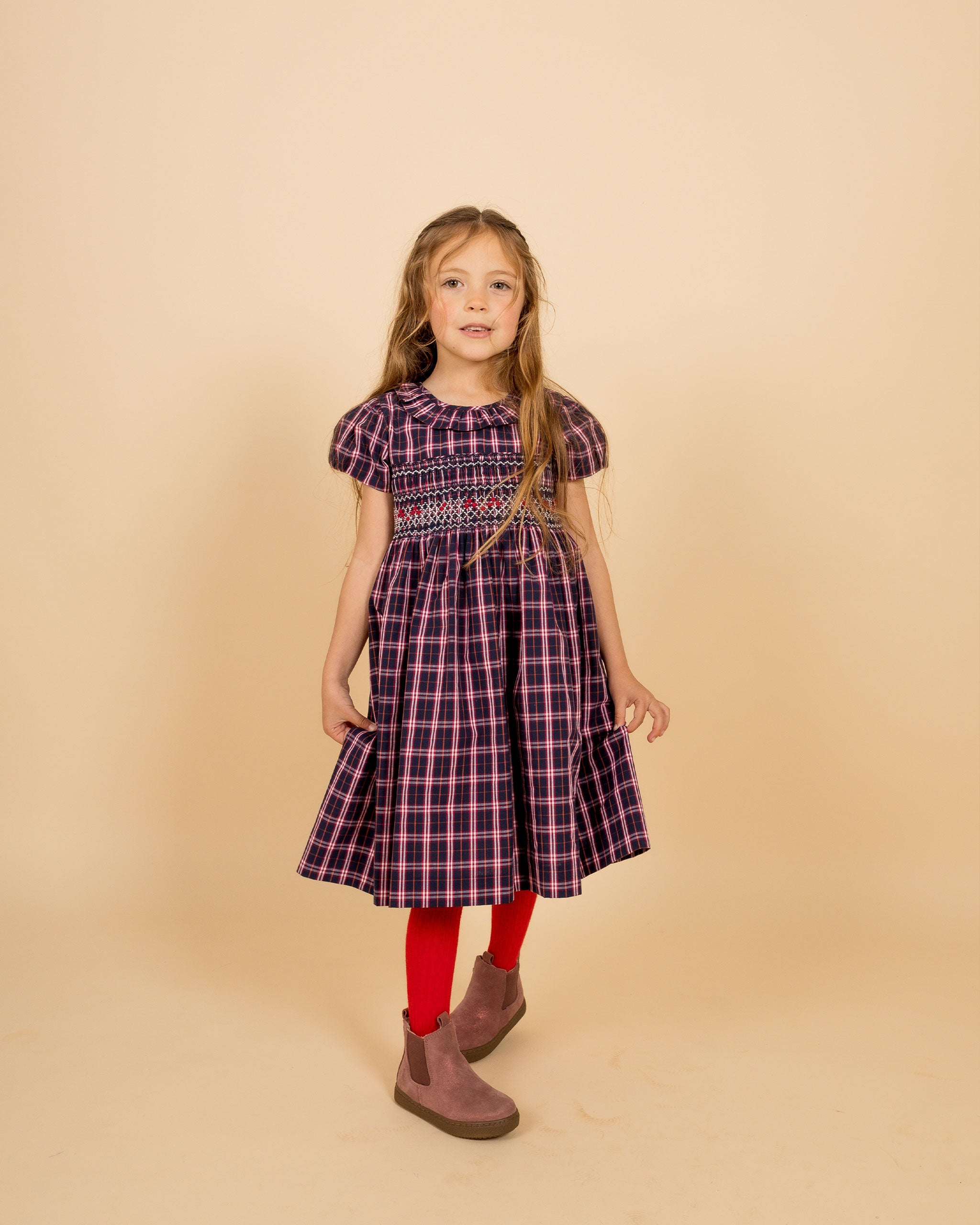 girl in navy tartan dress with hand-smocking