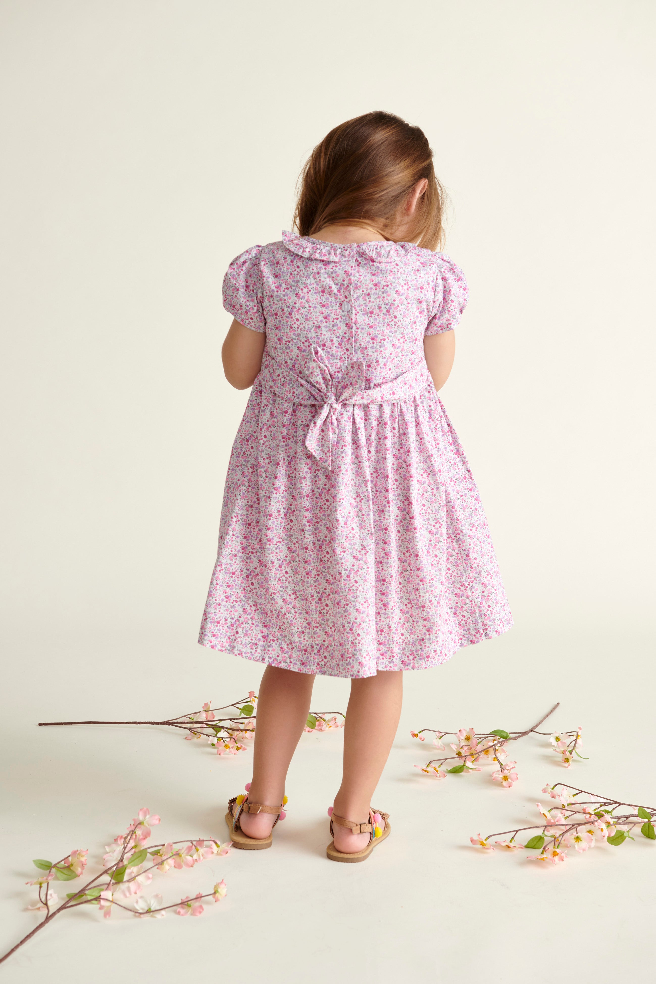 girl in floral smock dress, back view 