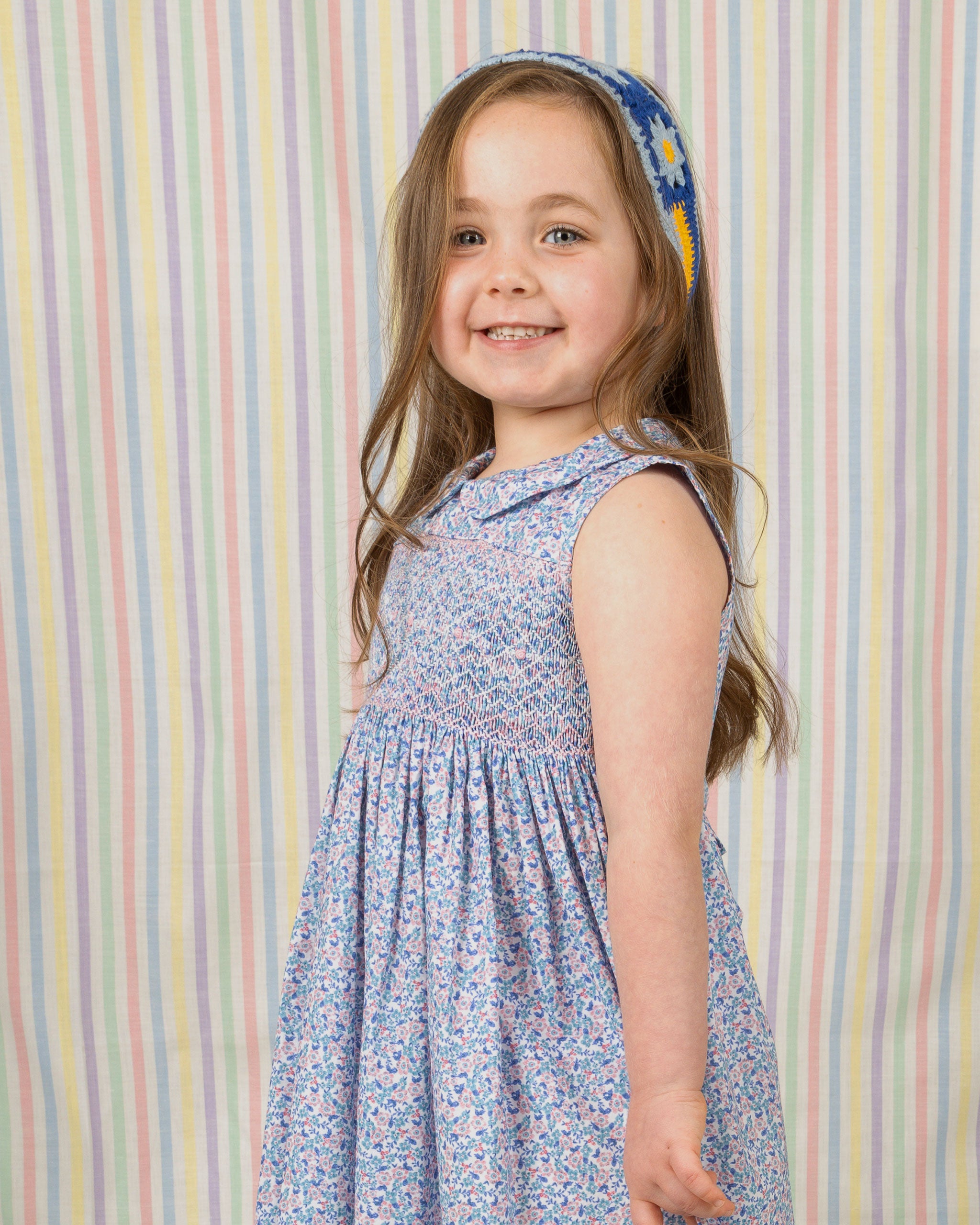 child model smiling in hand smocked dress, floral, blue
