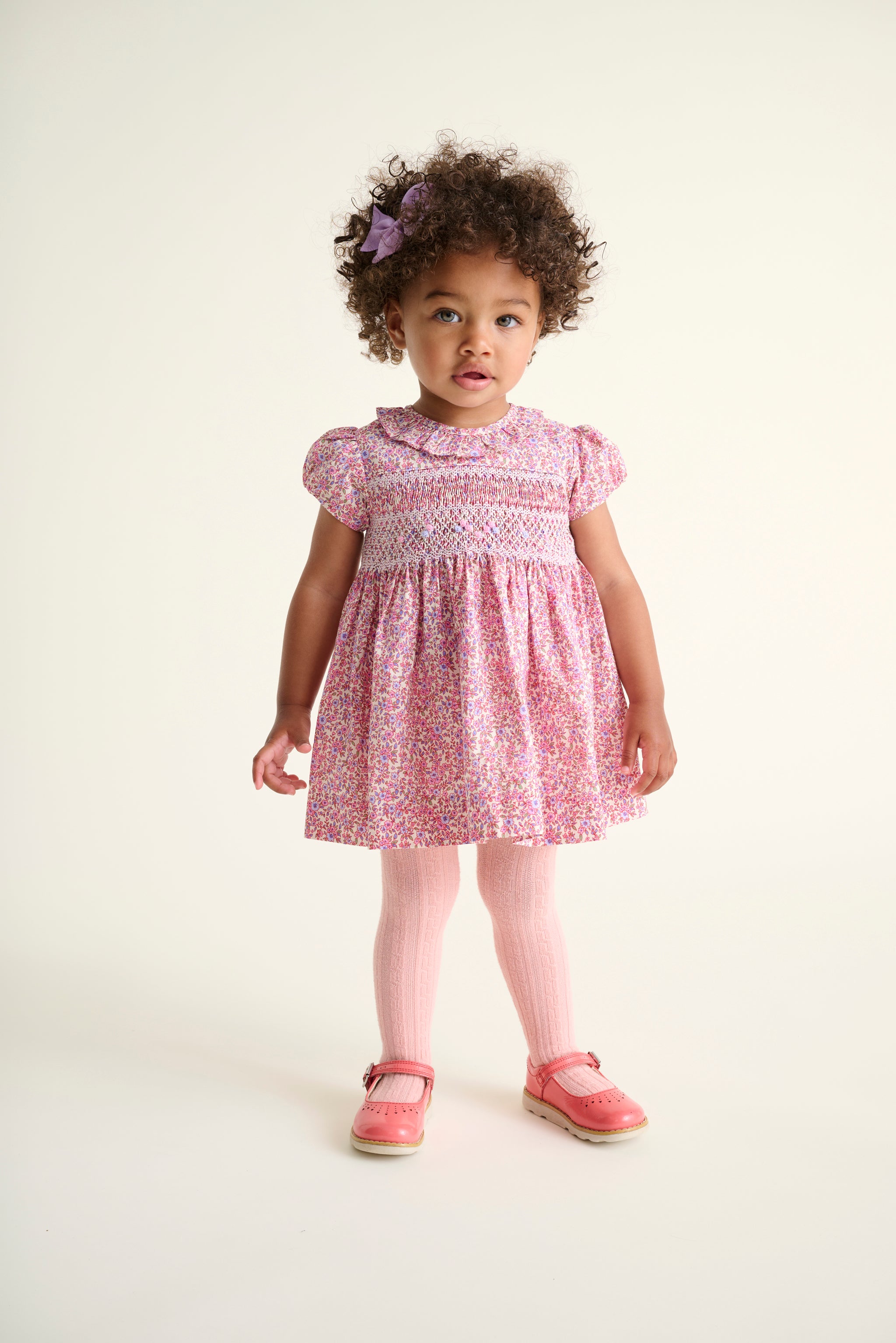 Toddler girl wearing a pink dress withheld smocking and frill collar