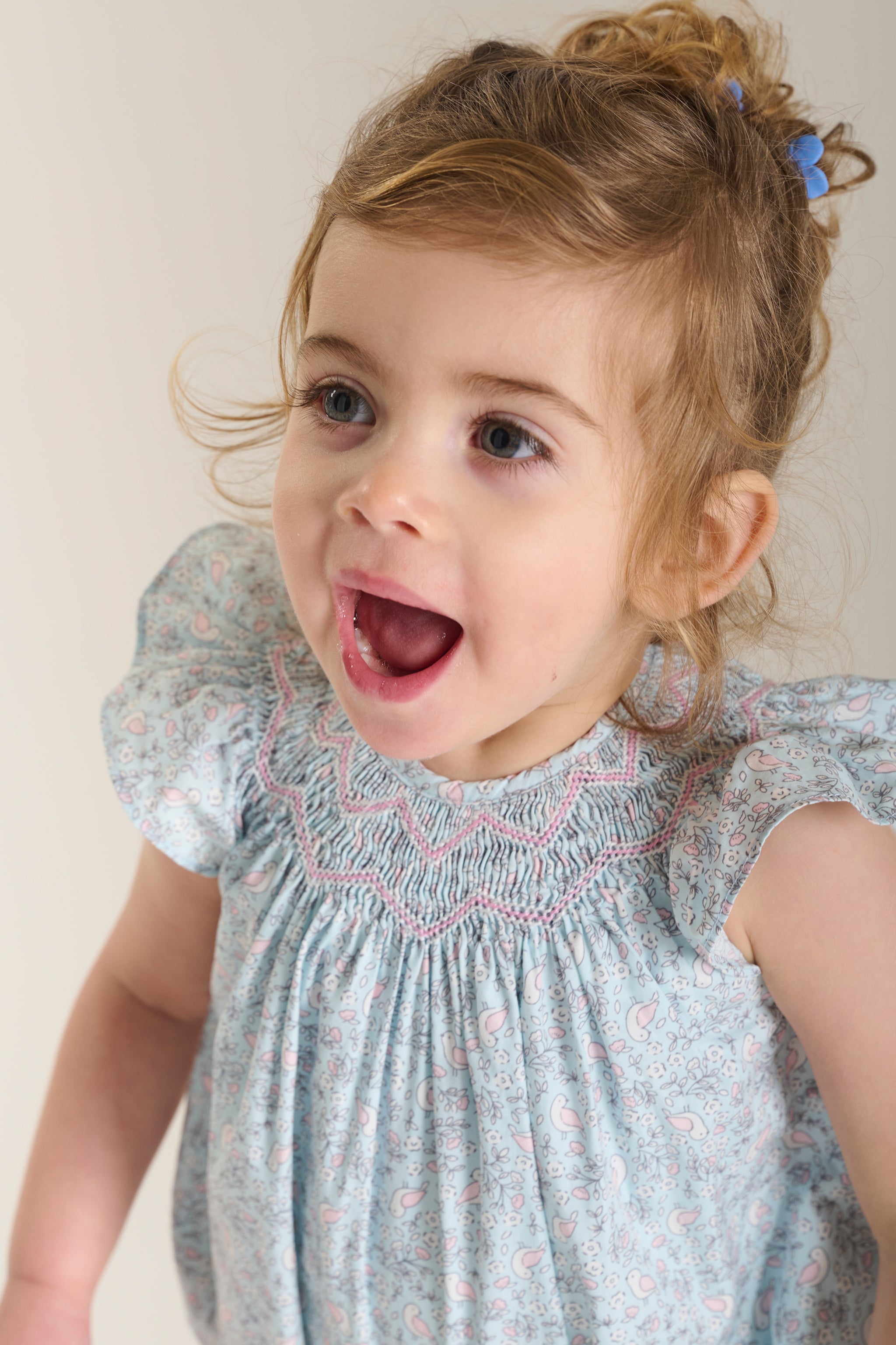 Child wearing a baby blue romper with bird  patterns 