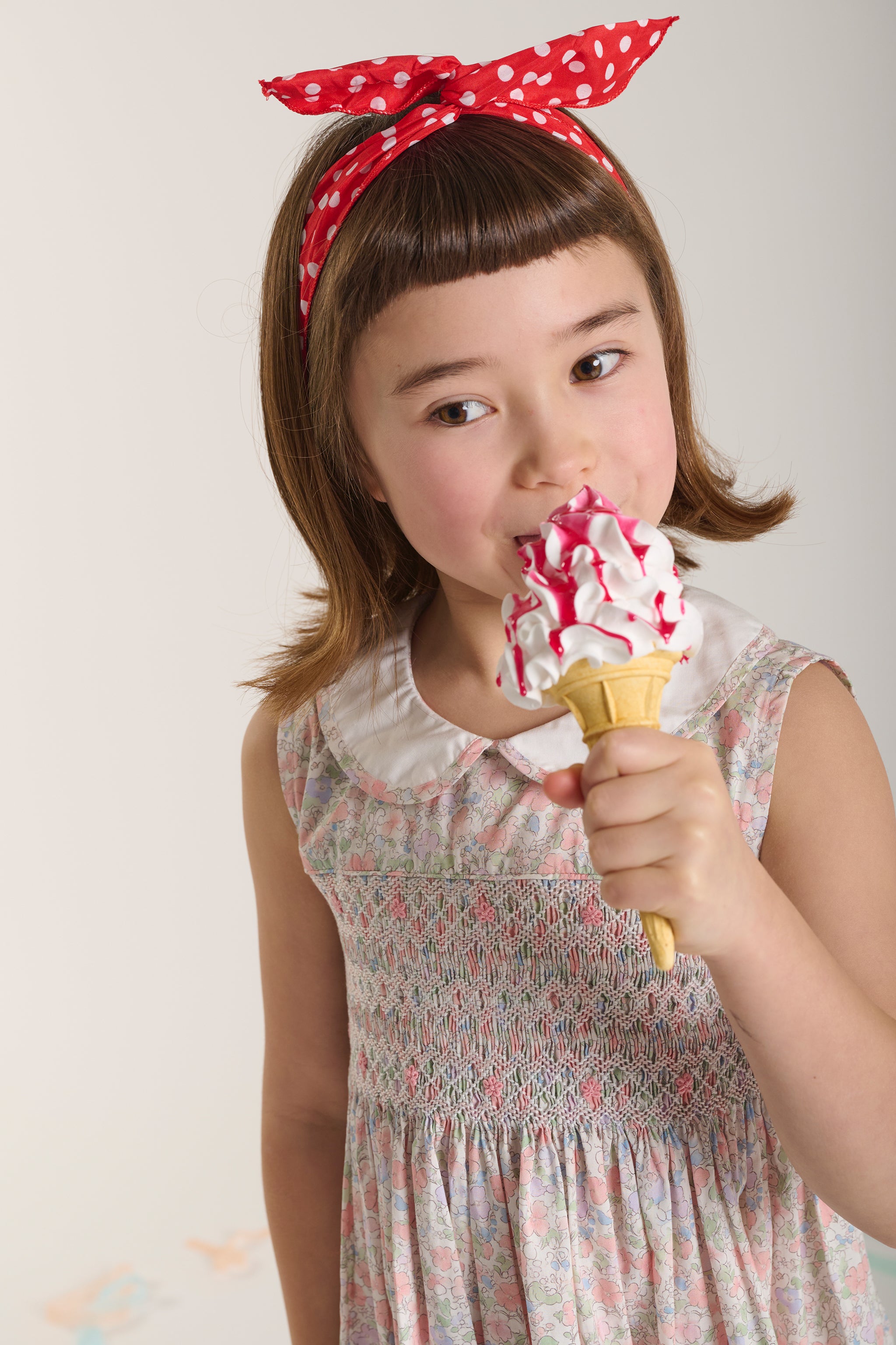 Young girl eating a ice cream cone wearing a hand-smocked dress