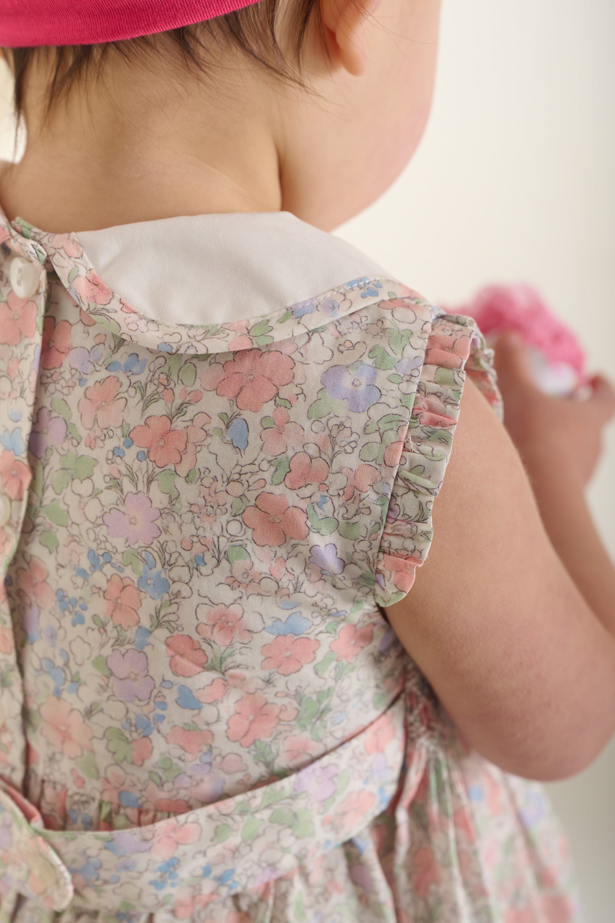 collar and detail of floral smock baby dress worn by baby girl