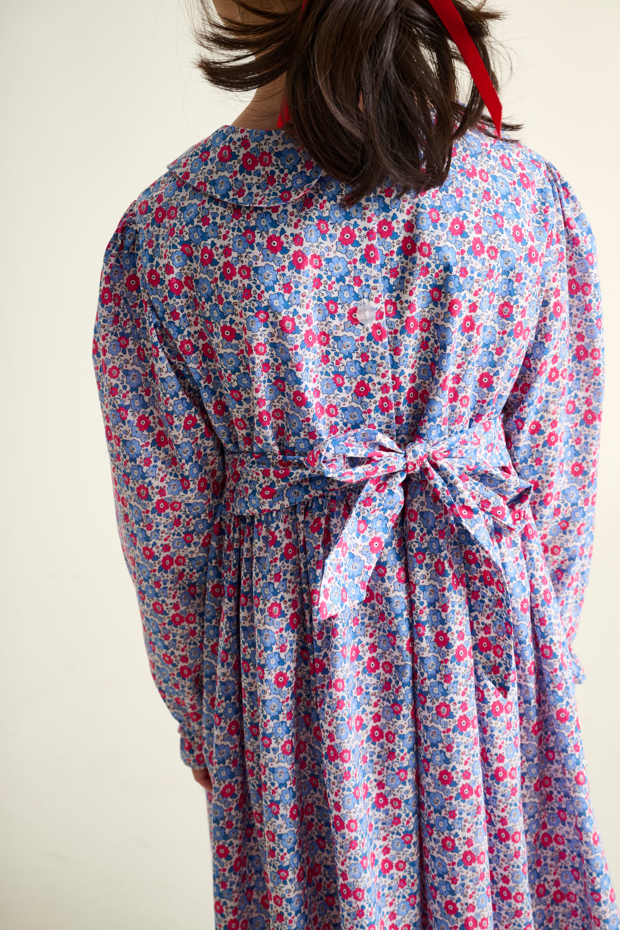 Person wearing a floral dress with a plain background