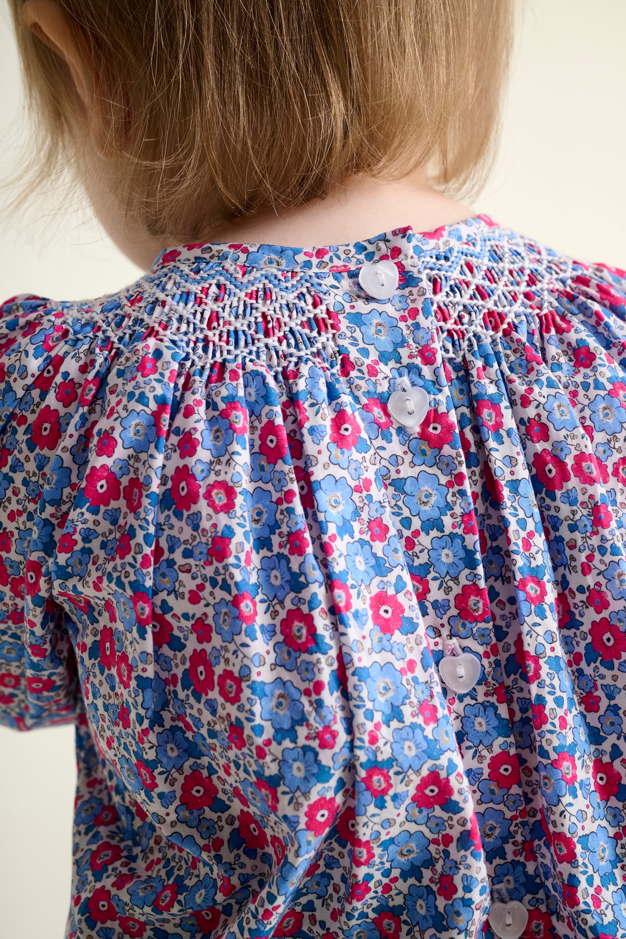 Close-up of a child wearing a floral dress with a white background